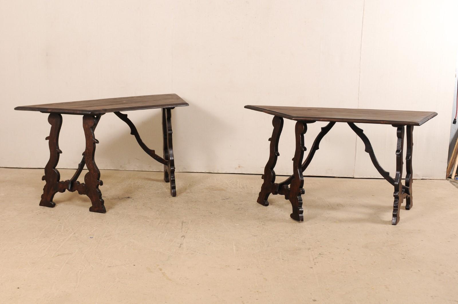 A vintage pair of Italian demilune tables with lyre-shaped legs. This pair of demilune tables from Italy each feature a halved-octagon shaped top which is raised upon a pair of sinuously carved and canted lyre-legs. The lyre legs are braced with two