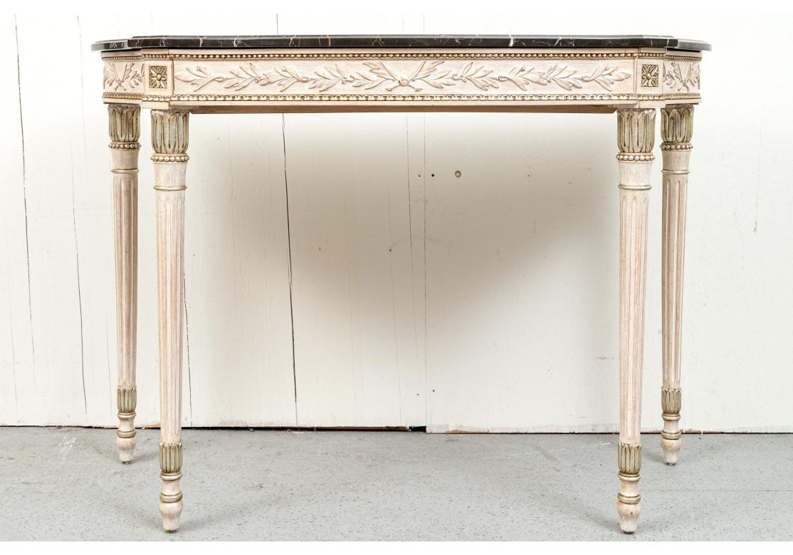 Pair of fine Italian carved Demi Lune Tables in a white wash finish having contrasting variegated black marble tops with cantered corners and a frieze drawer. The demilunes with carved foliate designs and corner flowers, flanked by bead and carved