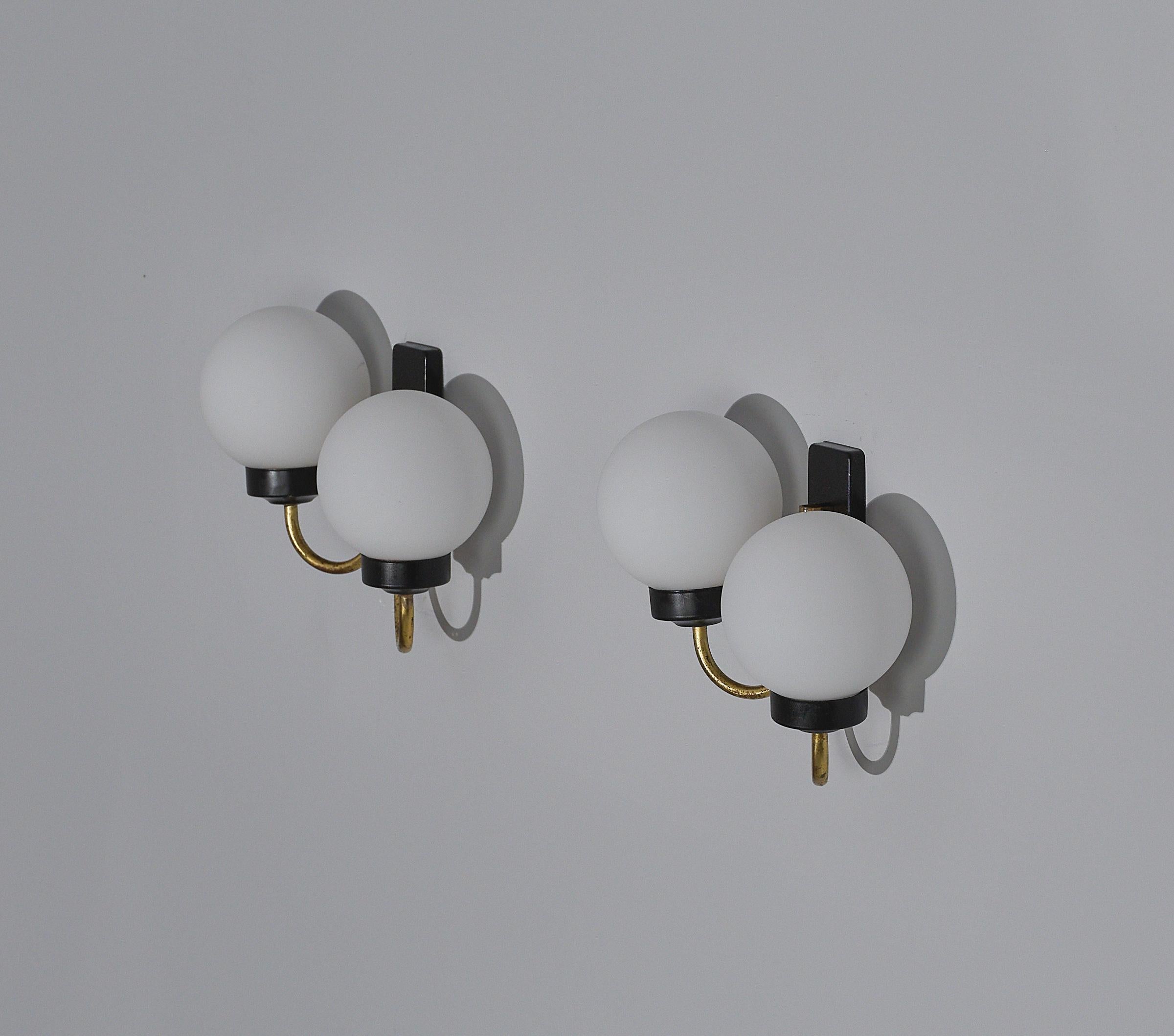 Presenting this exquisite pair of wall sconces, showcasing authentic Italian design from the 1950s. Crafted in brass and coated in black lacquer, these vintage pieces exude a timeless charm that seamlessly blends mid-century aesthetics with