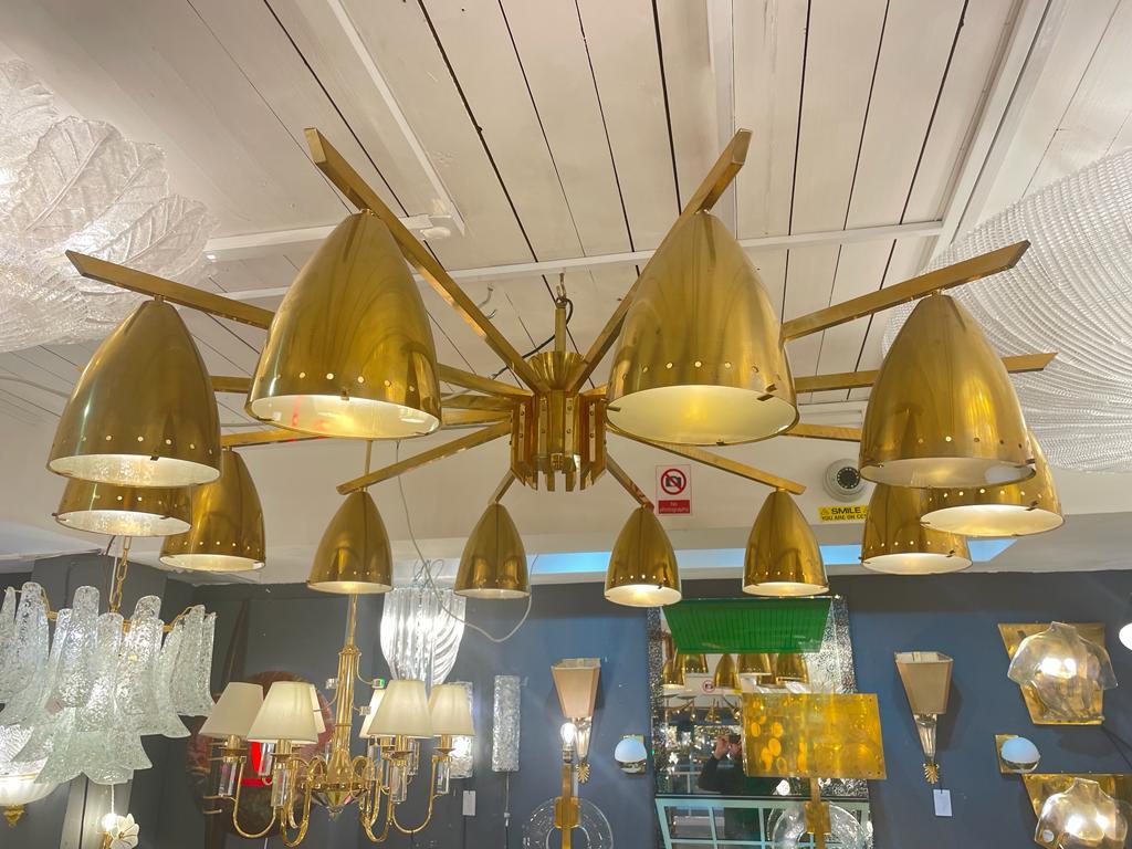 A stunning oversized Italian designed chandelier in brass 12 arms with glass lens detail of monumental proportions.

The chandelier is currently hanging on a short rod which can be changed to a new height of 100 cm