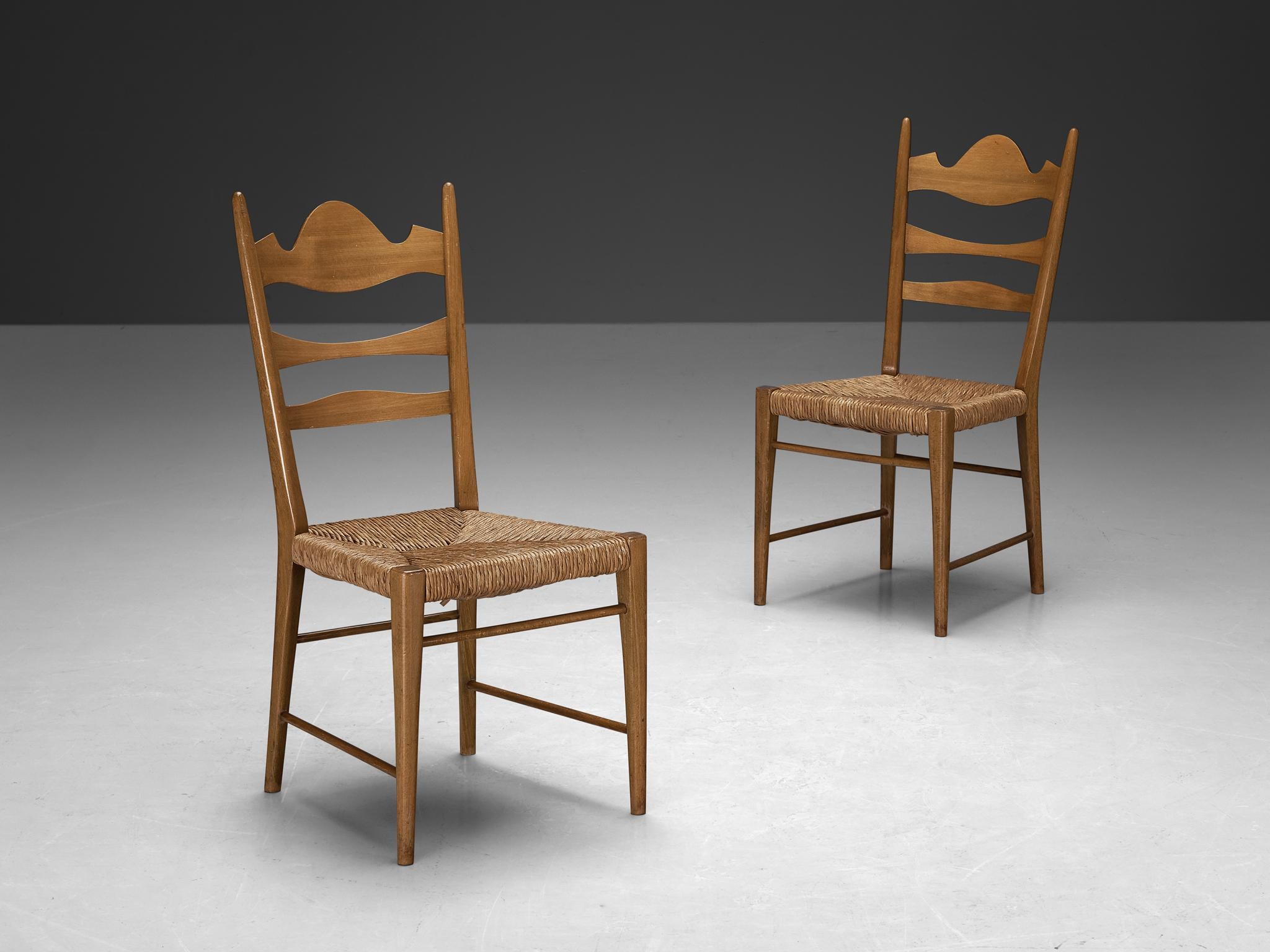 Pair of dining chairs, beech, straw, Italy, 1950s

Crafted with a refined decorative allure and a rustic inclination, these chairs present exquisite craftsmanship and intricate woodcarvings, showcasing a unique design. The backrest features