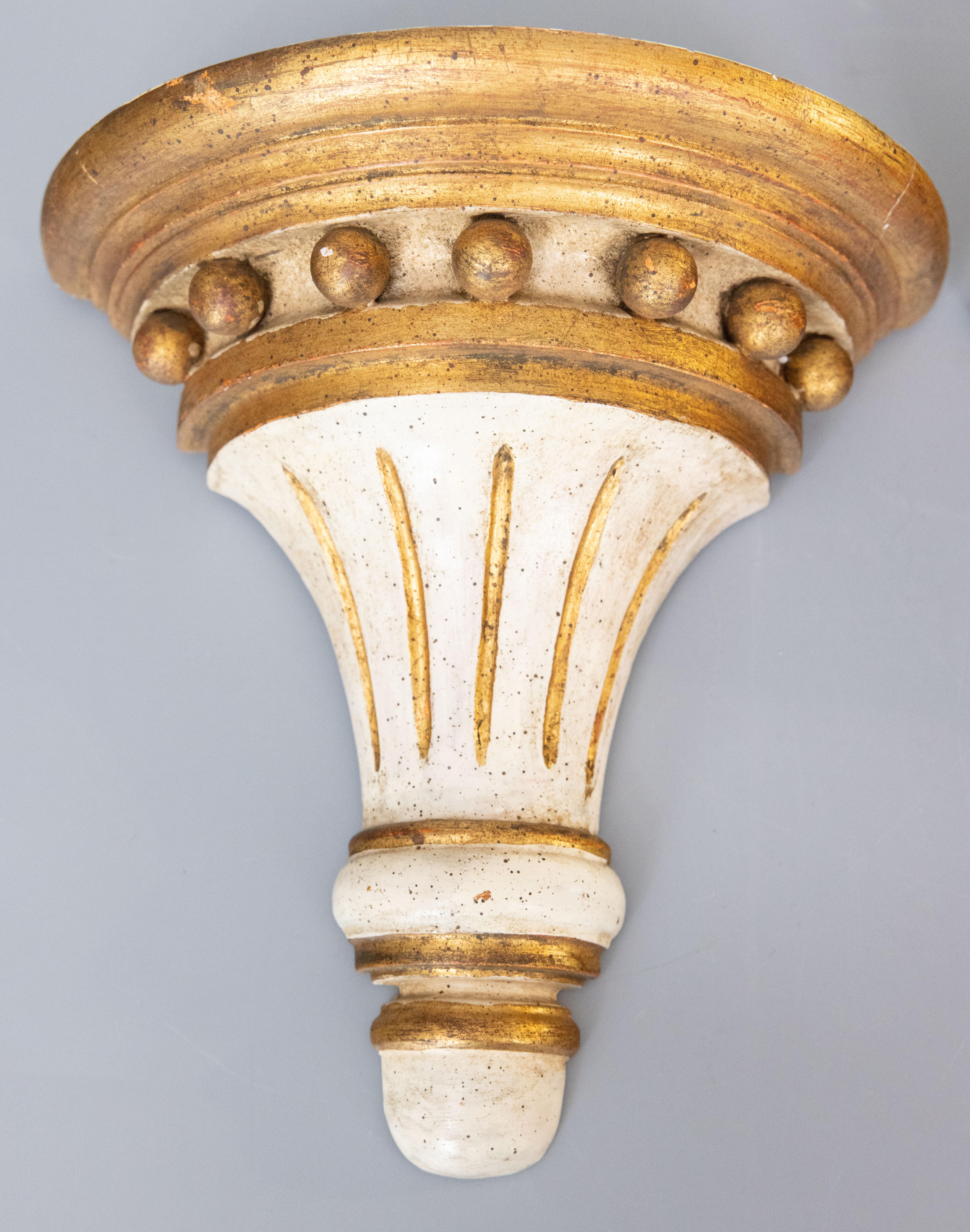 A gorgeous pair of vintage Italian Neoclassical style gilt wood wall brackets or corbels with a lovely patina, circa 1950. These stylish brackets have a lovely aged white and gilt fluted design with gold spheres, perfect for the modern home.