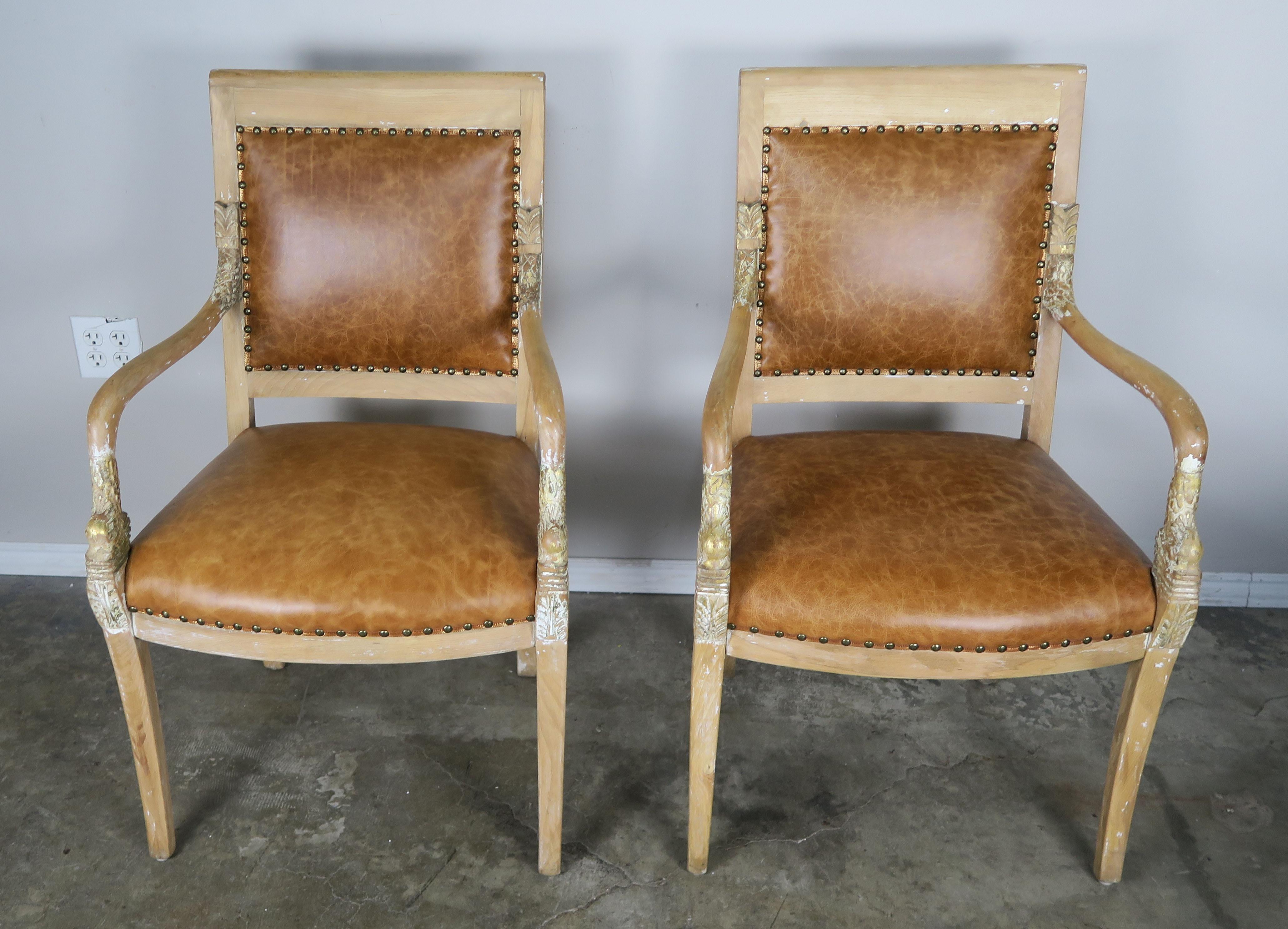 Pair of Italian painted and parcel gilt carved wood armchairs with dolphin motif arms. Leather upholstered with leather gold embossed Greek key gimp with spaced nailhead trim detail. Only remnants of paint and gold leaf throughout.
Measures: Seat