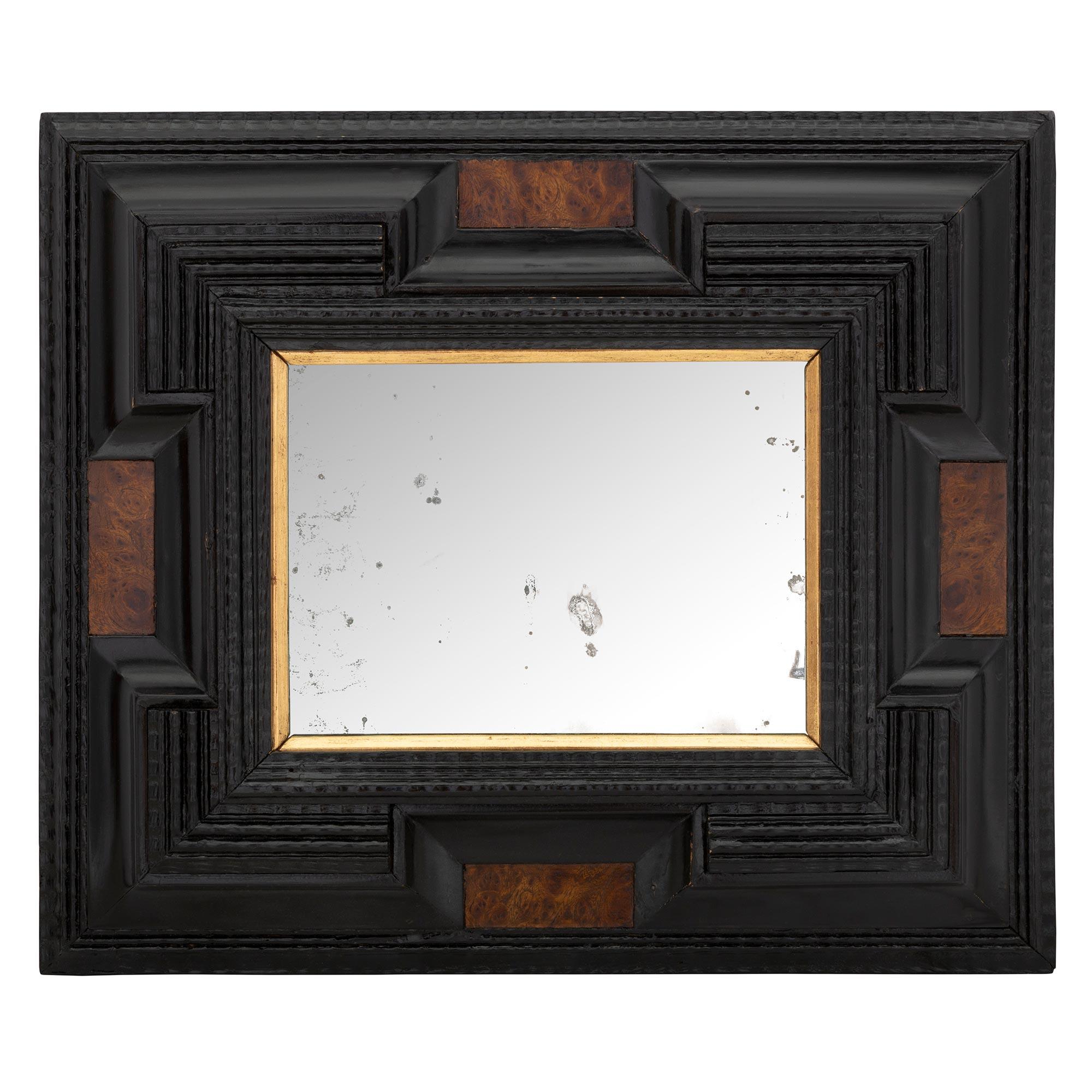 A striking and most charming pair of Italian early 18th century ebony, burl walnut, and giltwood Florentine mirrors. Each mirror retains its original mirror plate set within a fine giltwood band and impressive ebony frame with a striking and