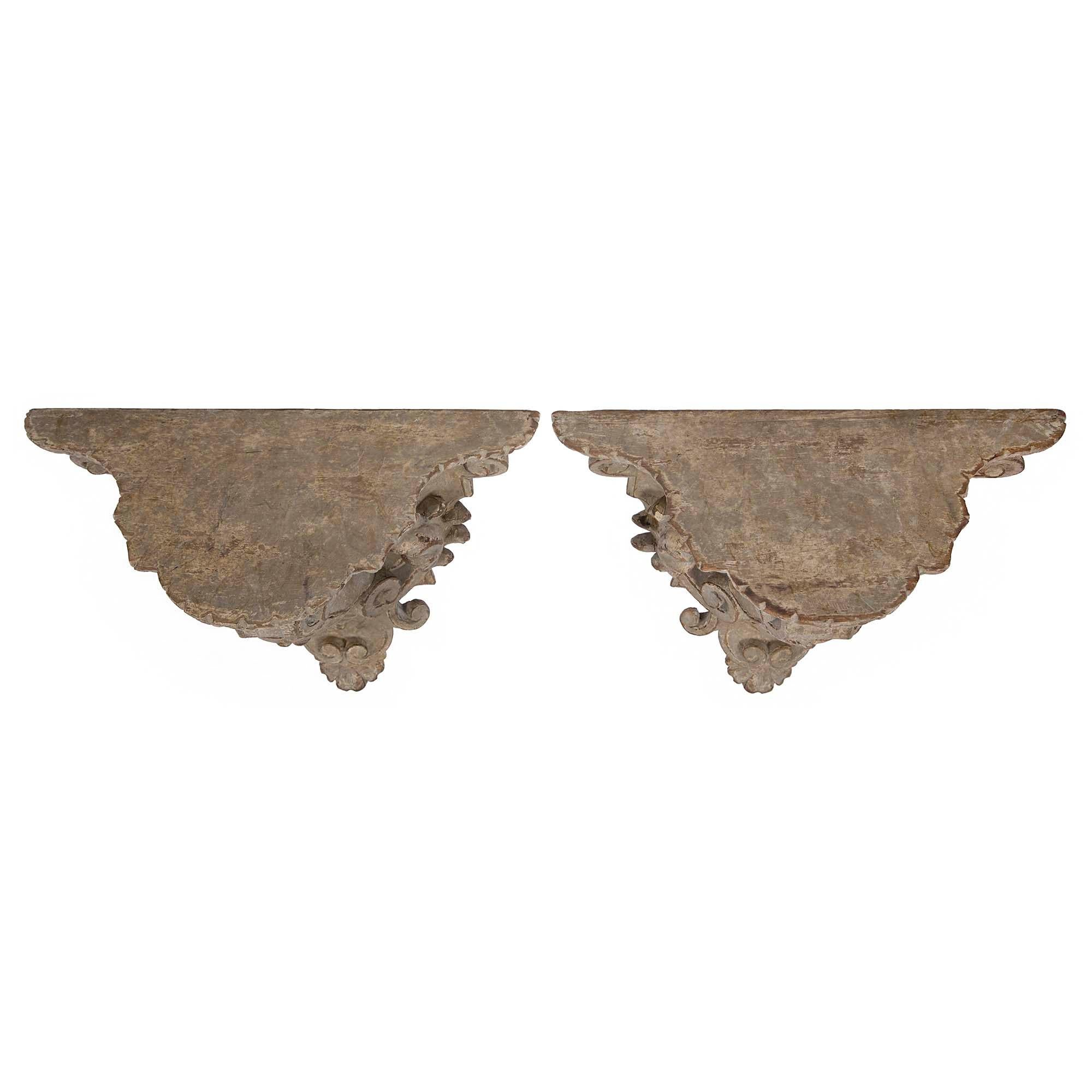 A pair of very handsome Italian early 19th century patinated Venetian wall brackets. Each wonderfully carved wall bracket has a scrolled foliate design centered by charming masks. With all original patina throughout and large contoured top