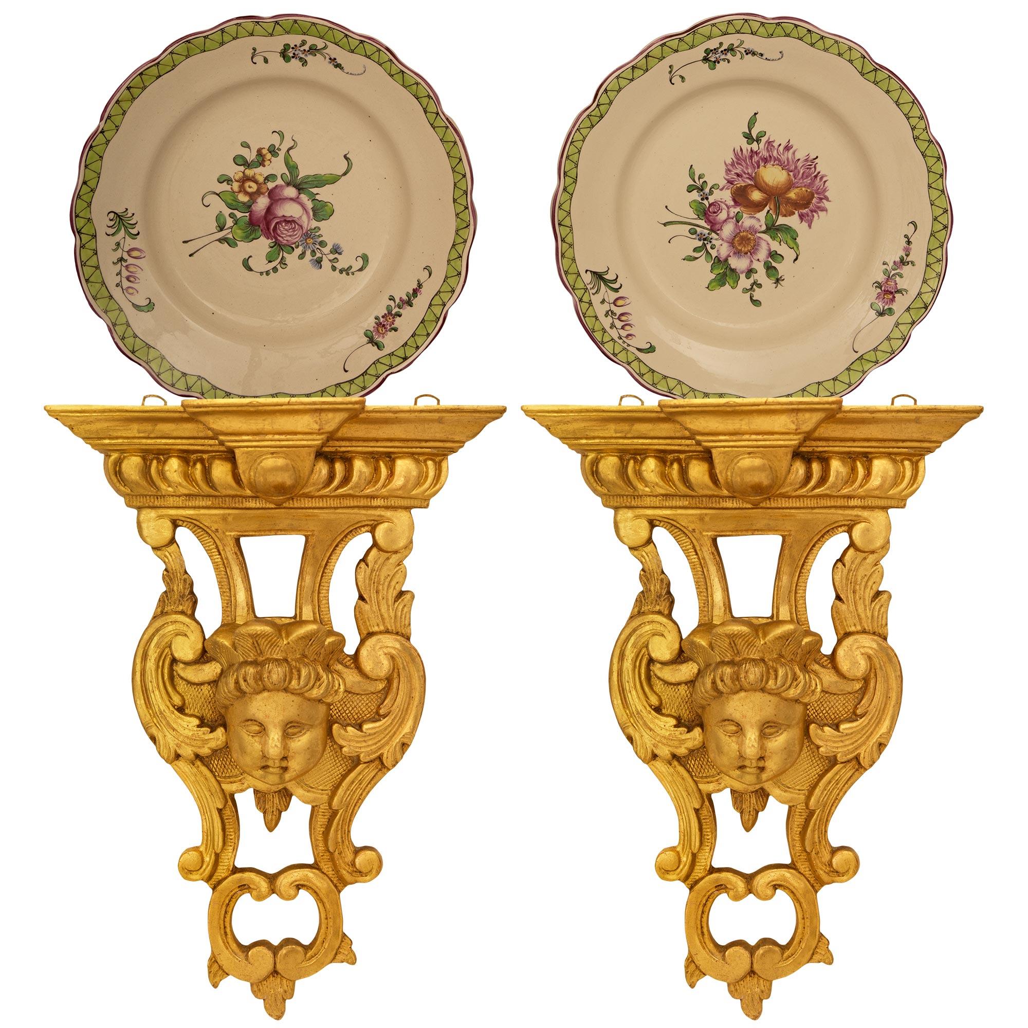 A lovely pair of Italian early 19th century Louis XVI st. Giltwood wall brackets. Each beautiful wall bracket displays a finely carved bust of a cherub with palmettes atop his head and surrounded by scrolling foliate designs accented by reeded and