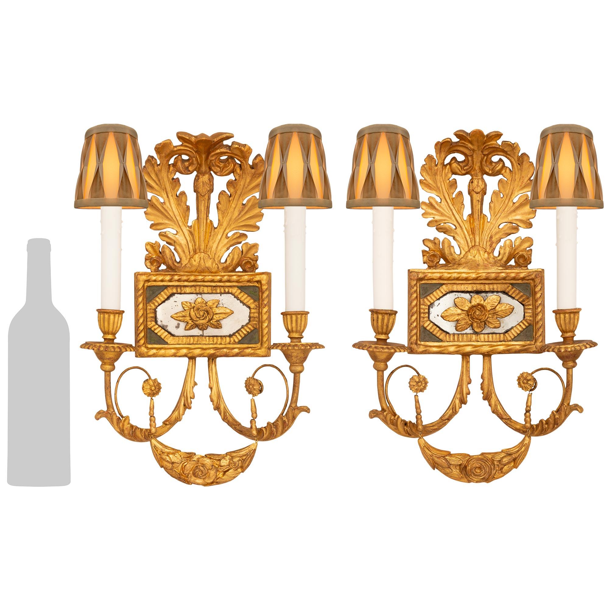 A stunning and most charming pair of Italian early 19th century Neo-Classical st. Giltwood and patinated wood mirrored sconces. Each wonderful two arm sconce is centered around a rectangular mid section with carved twisted edges. Inside the