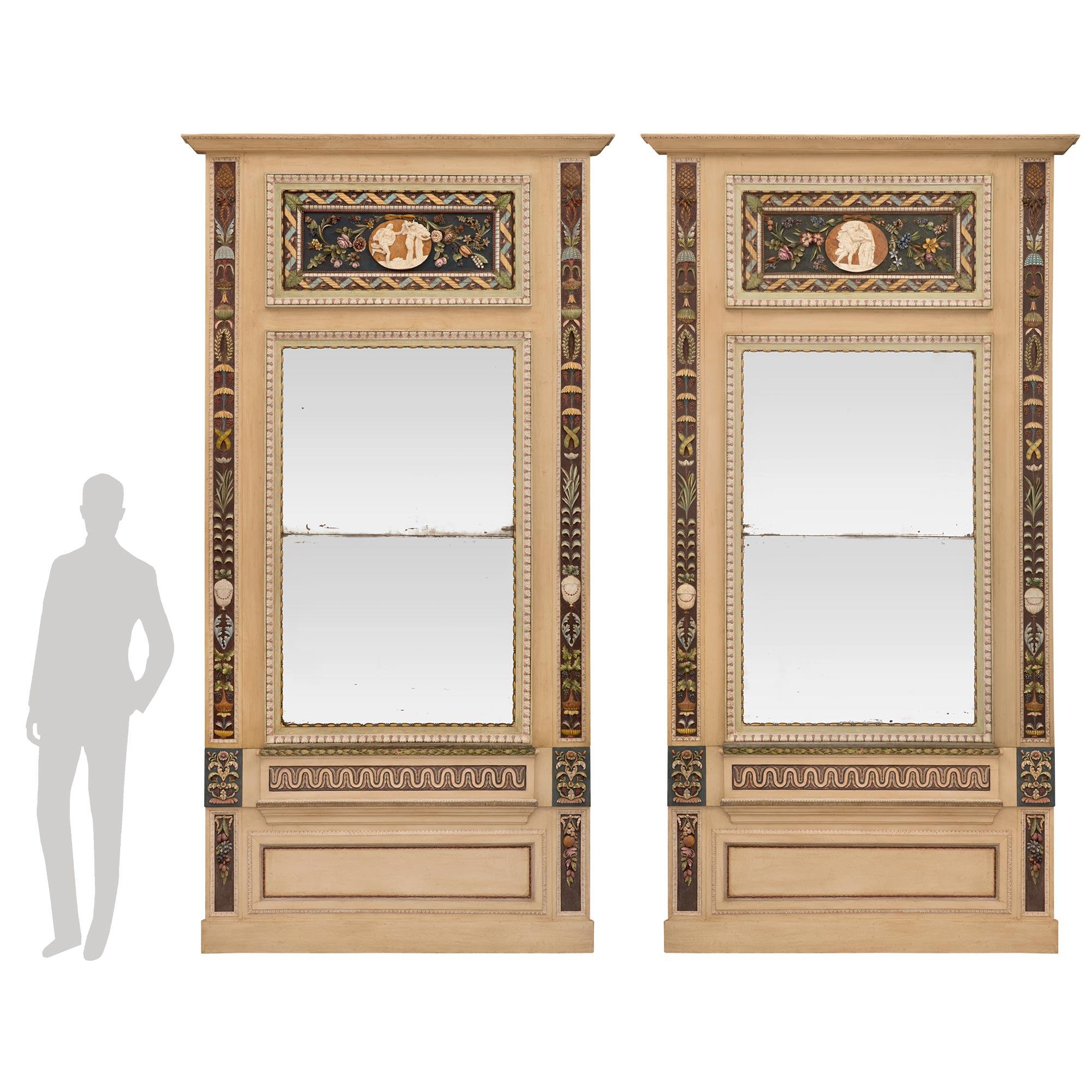 A stunning and extremely decorative large scale true pair of Italian early 19th century neo-classical st. patinated wood trumeau mirrors. Each mirror is raised by an elegant mottled base below a recessed panel framed within a fine foliate border