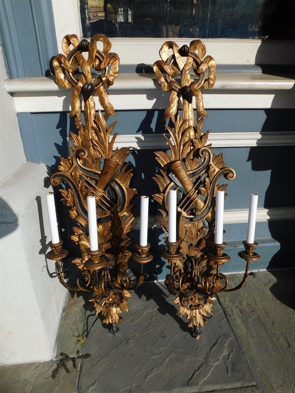 Pair of Italian flanking ebonized musical lyre with ribbon gilt wood and gesso three arm foliage wall sconces, Mid 19th Century. Pair were originally candle powered and have been electrified.