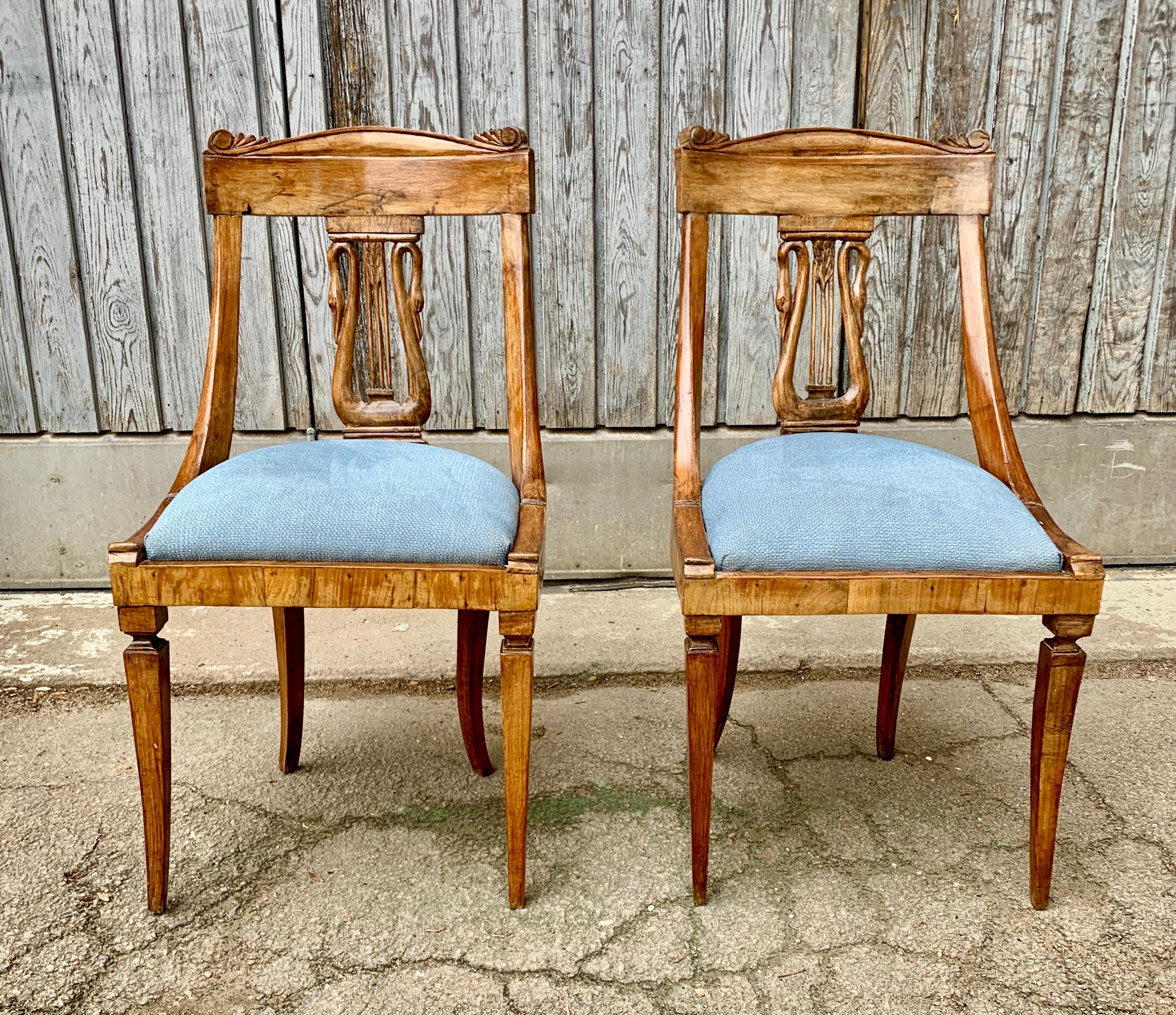 A pair of Italian early 19th Century Empire dining chairs in solid walnut.
This Tuscan pair of chairs, with swan decoration on the back, was likely crafted in the city of Lucca. This town is well known for its furniture and bronzes of that period.