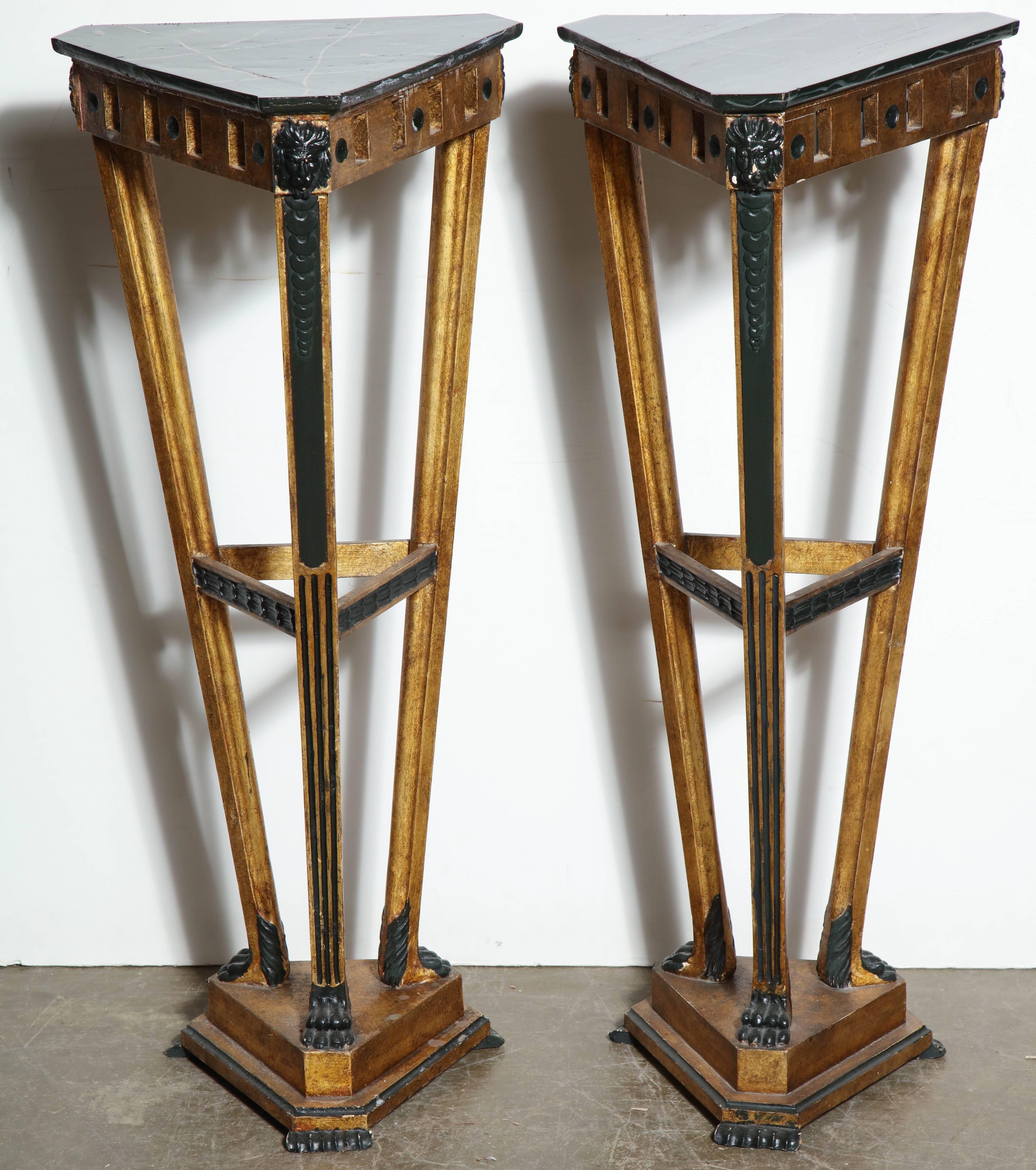 Pair of Italian Empire style gilded and faux marble top triangle form pedestals with pierced aprons and lion head and paw feet carving.