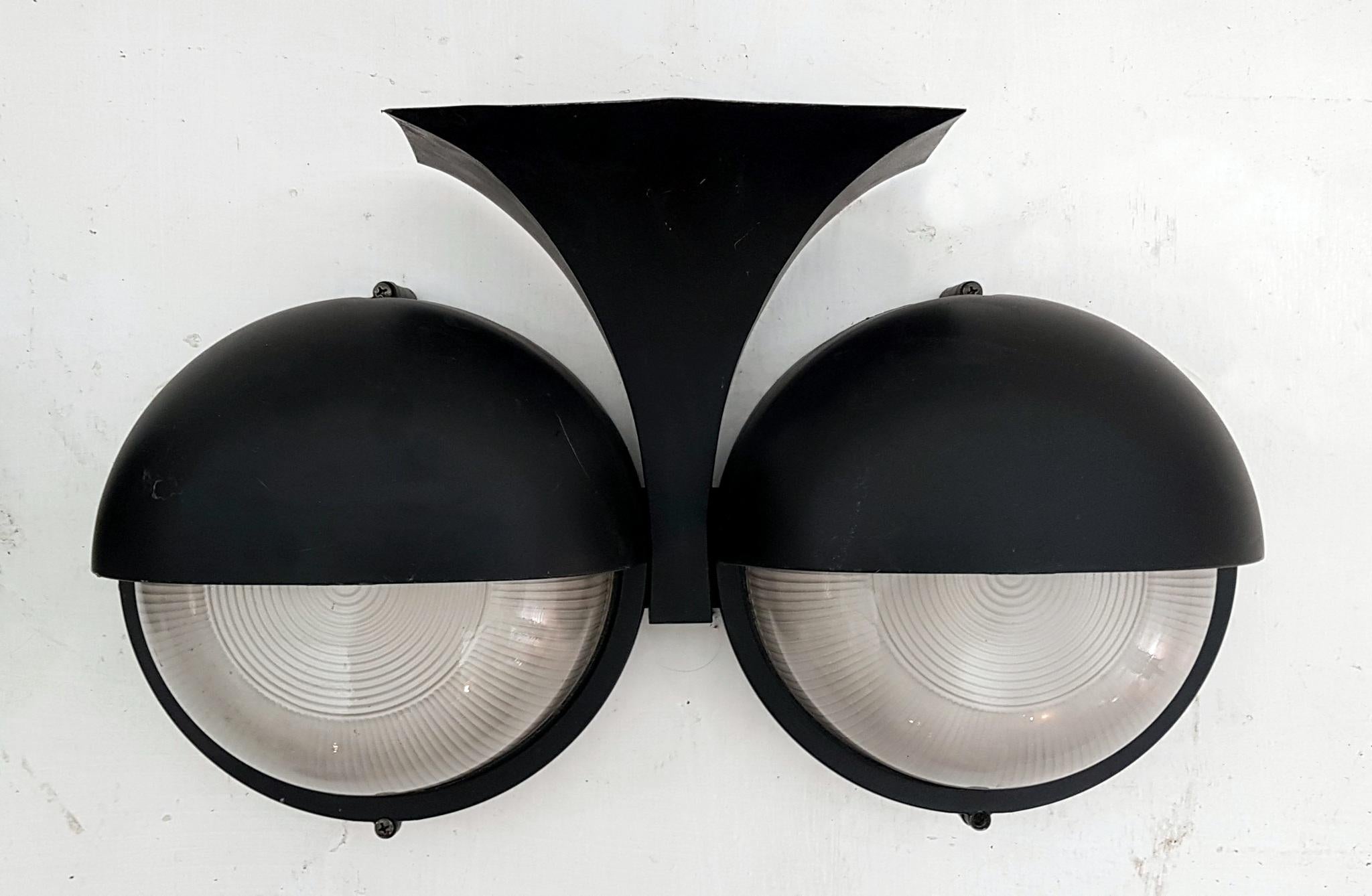 A pair of black wall sconces in cast aluminium made for exterior use. Each sconce has two heavy set pieces of glass concealing a lightbulb each. Will work with screw in lightbulbs. Some scuff marks which is visible in the pics.