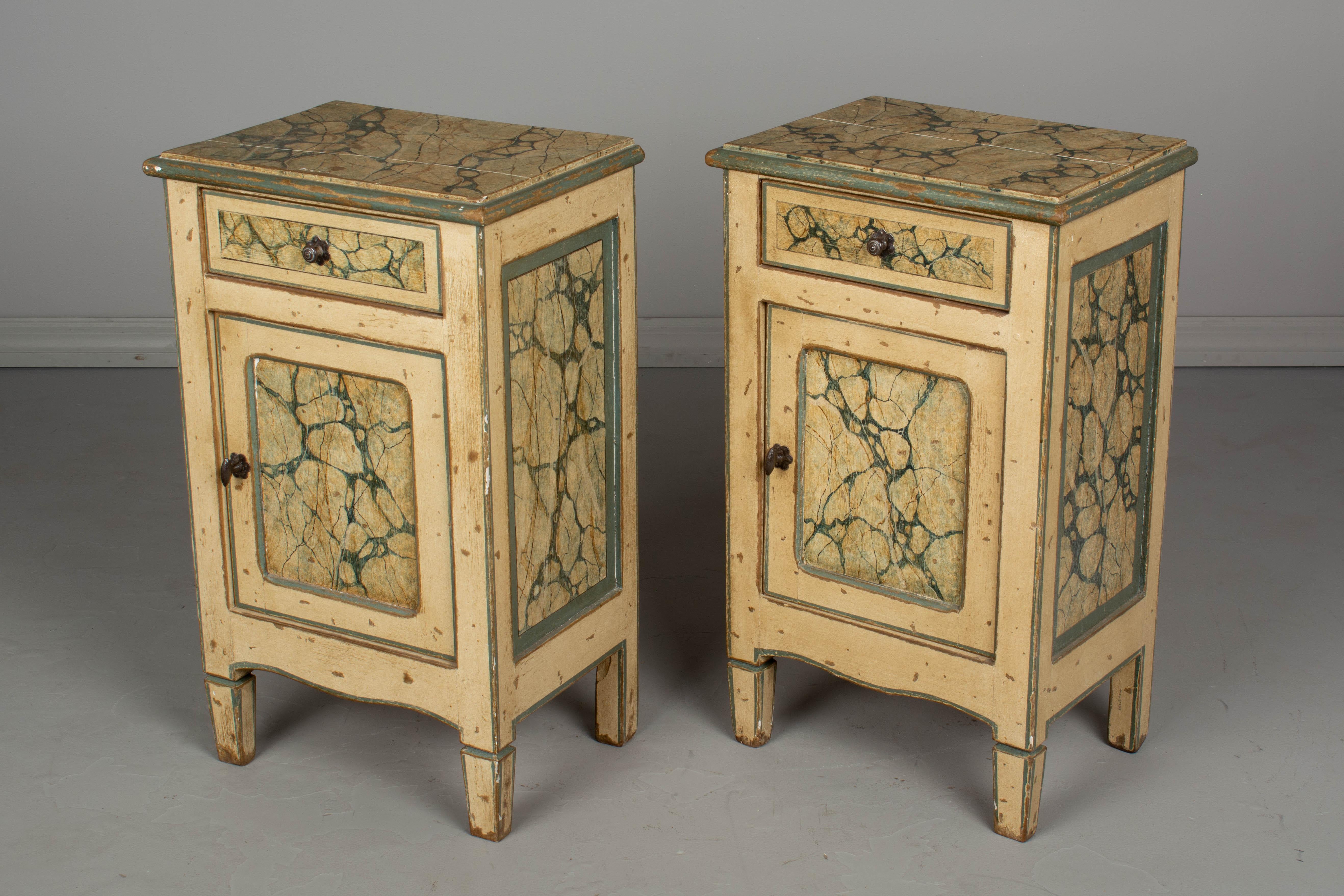 A pair of Italian Florentine style faux marble painted nightstands, or side tables. Made of pine, with a drawer above a cabinet door. In good condition, sturdy and well-crafted. Nice patina with minor paint loss. Please refer to photos for more