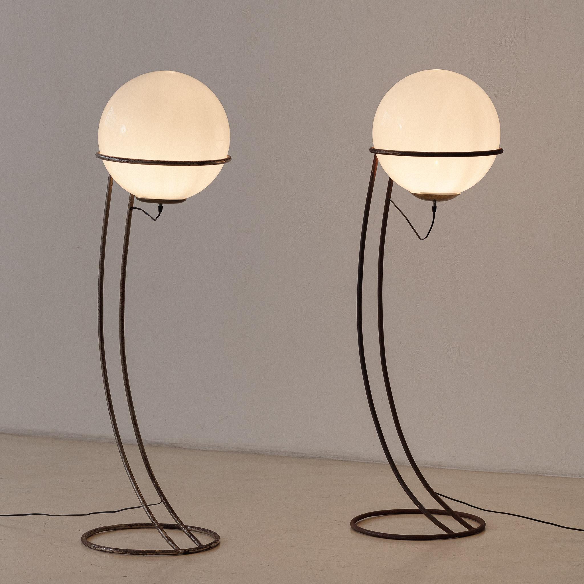 These floor lamps have their base as a curved iron tube with a loop that supports a big glass orb wired from below. The light source is smooth and diffused, ideal for creating a cozy mood.

The authorship is still on research by our team, but it