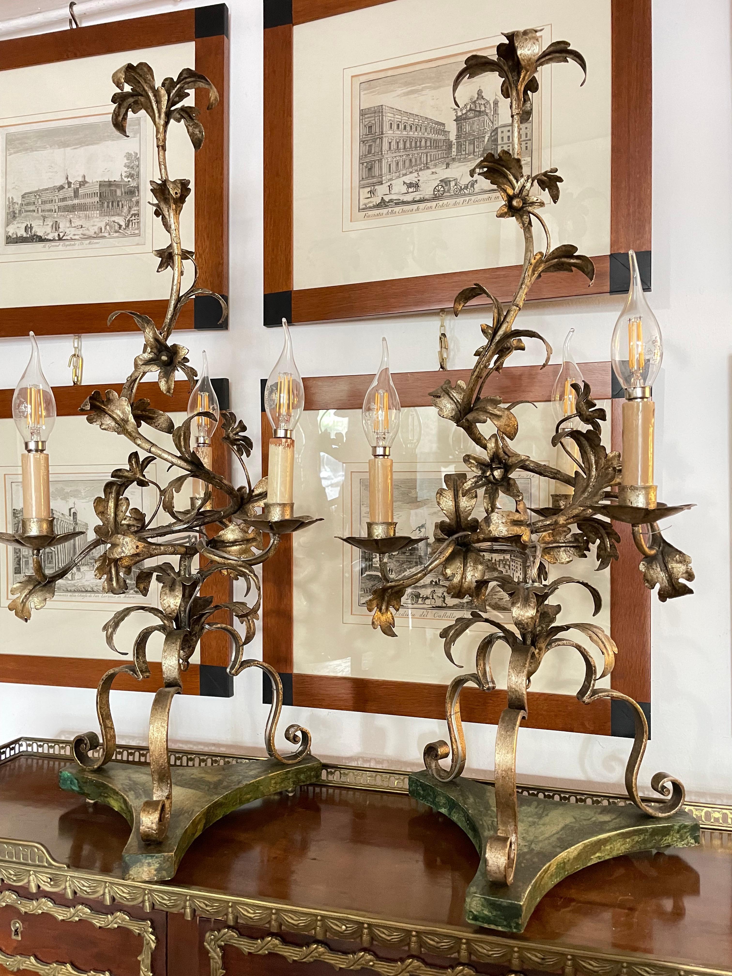 Pair of 20th century Italian wrought iron candelabra, with a warm beautiful mecca silver-leaf finish, two floral and foliate three-light table lamps, set on shaped wooden bases with green faux marble finish. 

Both artworks are fully handmade,