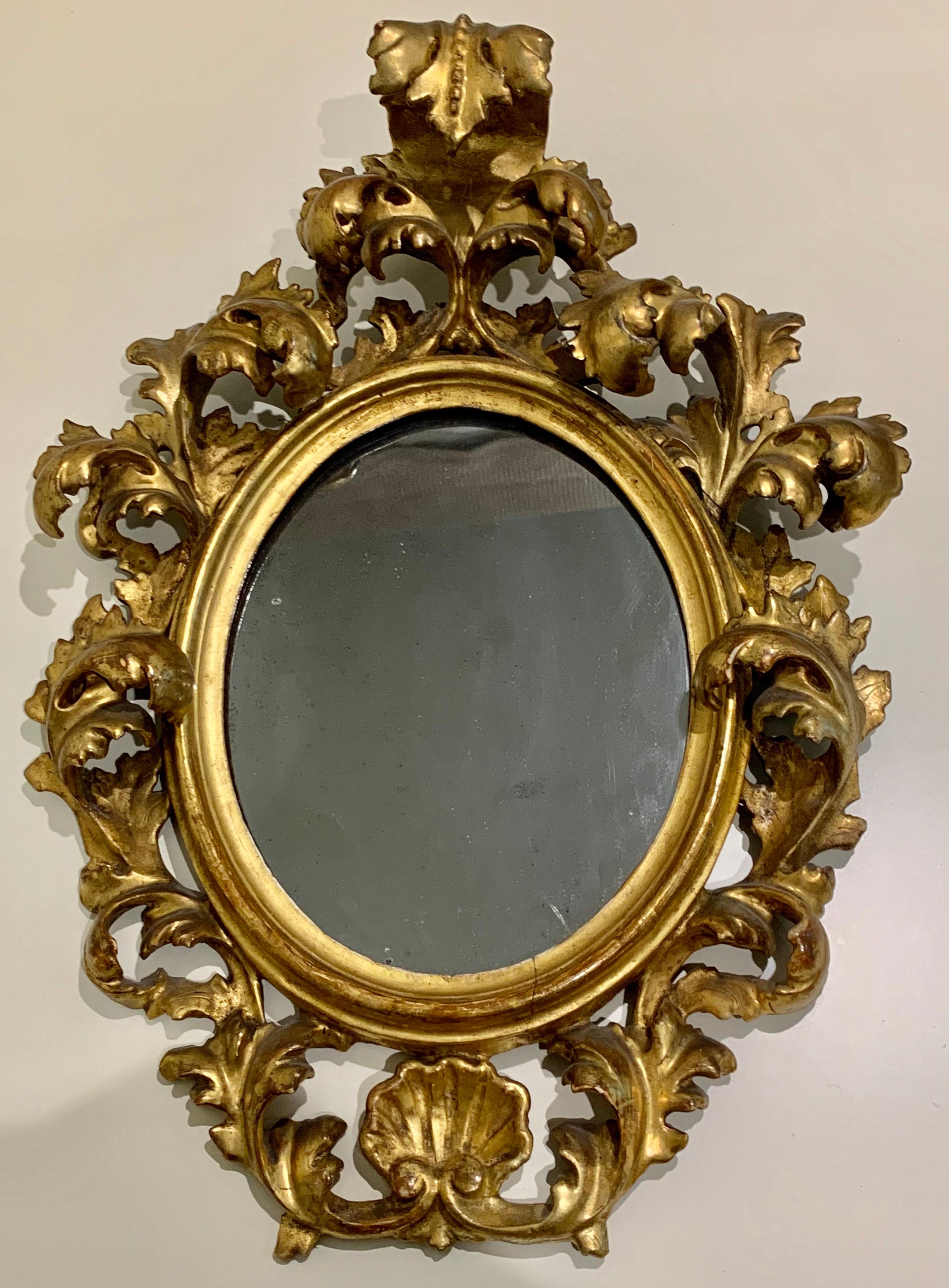 A rare to find matching pair. These Florentine gilt wood oval wall mirrors with a rococo acanthus scroll frame. Each of them feature an intricately carved giltwood frame crafted in the opulent Rococo style, with foliate decoration of acanthus