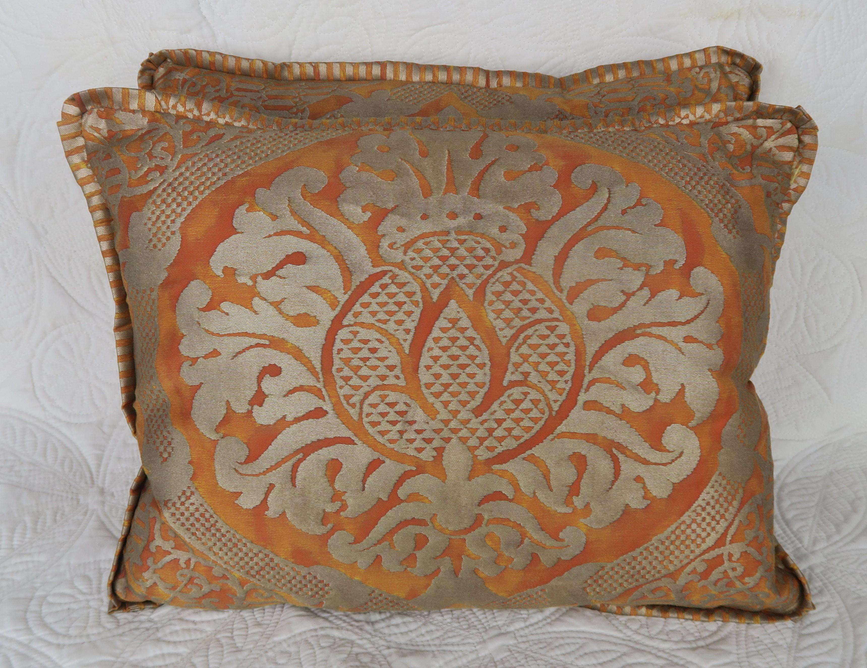 Pair of burnt orange and silvery gold Fortuny pillows with sunkist colored silk backs and flat welt detail. Down inserts, zipper closures.
     