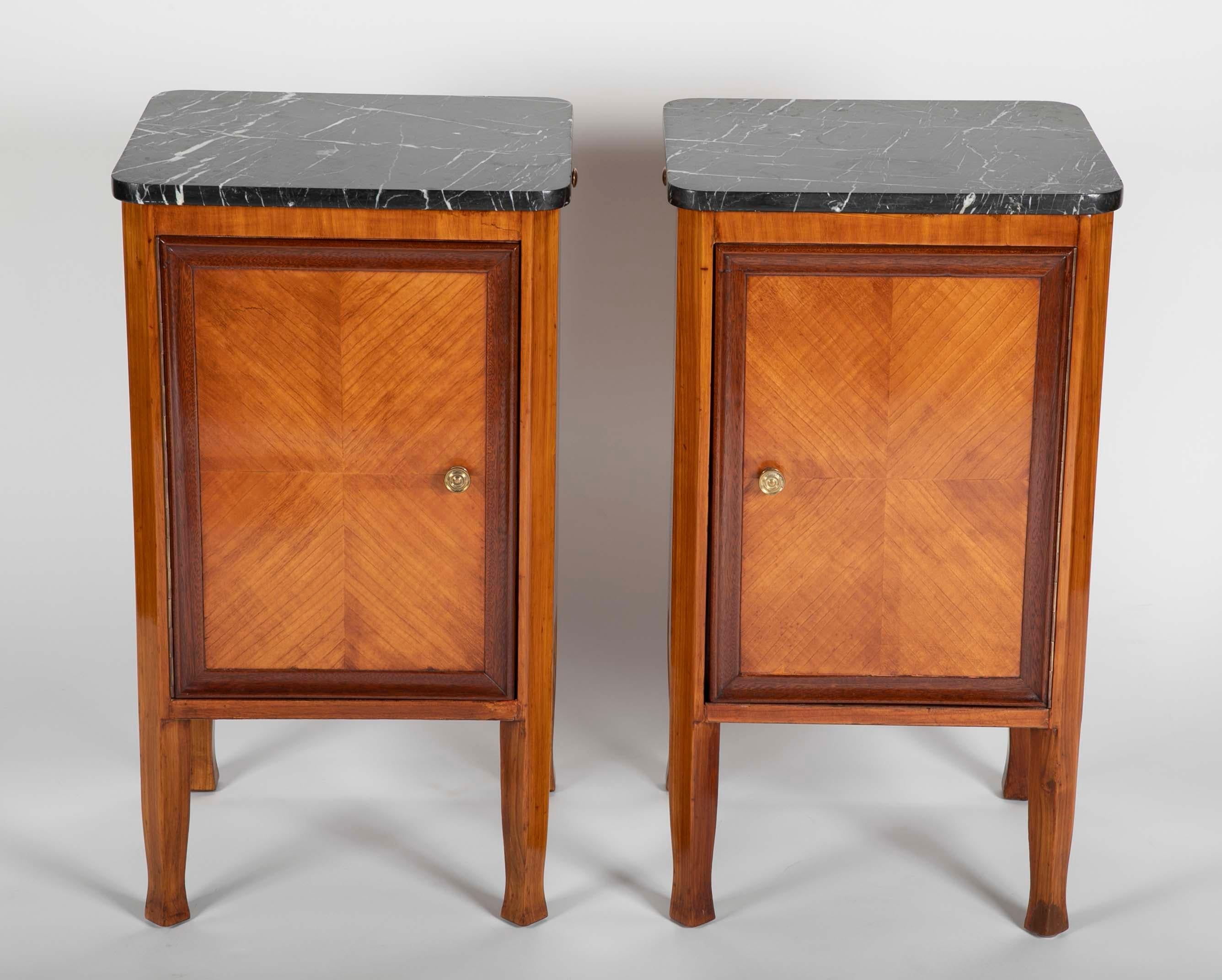 A very handsome pair of Italian midcentury night stands in the neoclassical style with black and white marble tops. The door of each cabinet opening in the opposite direction with a single shelf inside. A nice detail of these bedside cabinets is the