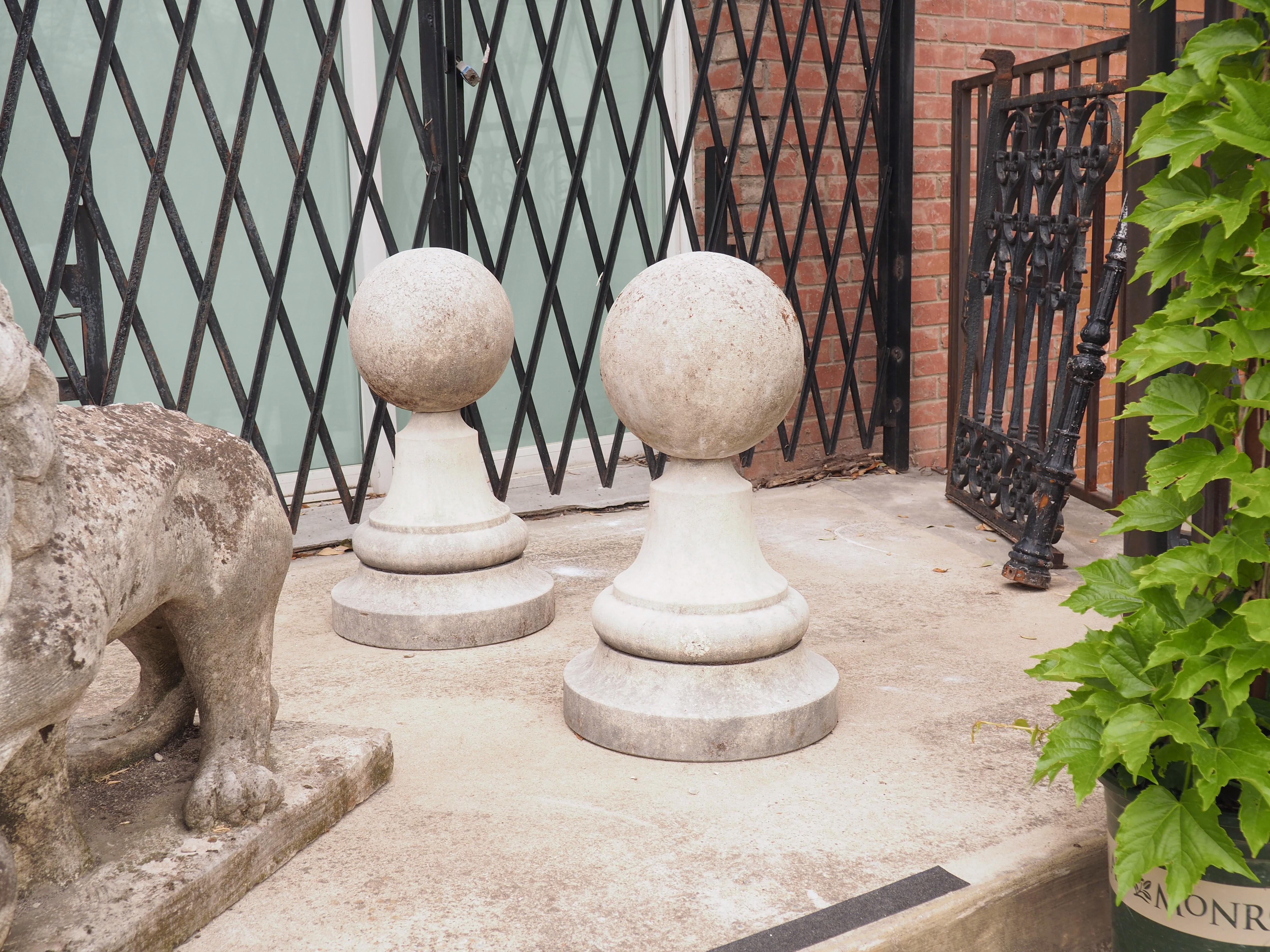 This large pair of garden ball finials have been hand-carved from Italian limestone. Ball finials such as this can often be seen flanking the entry of gardens at Italian villas. Both balls are roughly 14 ¾ inches in diameter and sit atop circular