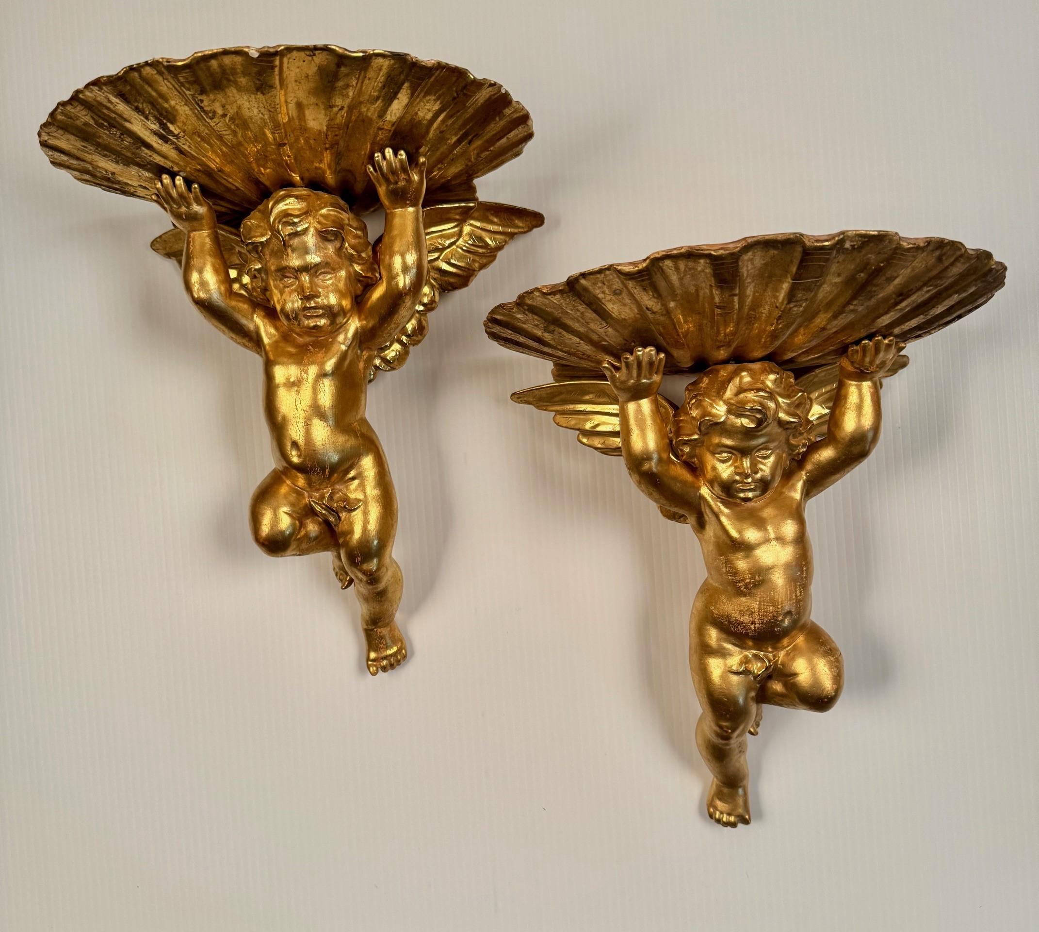 Each is modelled as a giltwood cherub with outstretched wings supporting a  shell. They are a true pair, one left and one right.  Cherubs by definition have wings, Putti have none. They  are often emblematic of love in a light-hearted way, They are