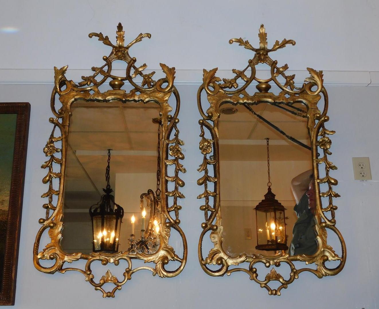 Paire de miroirs muraux en bois sculpté doré et gesso de style Chippendale anglais, avec motifs décoratifs de volutes et de feuillages. Vers 1770.  Les miroirs ont conservé leur verre argenté et leur support en bois d'origine. 