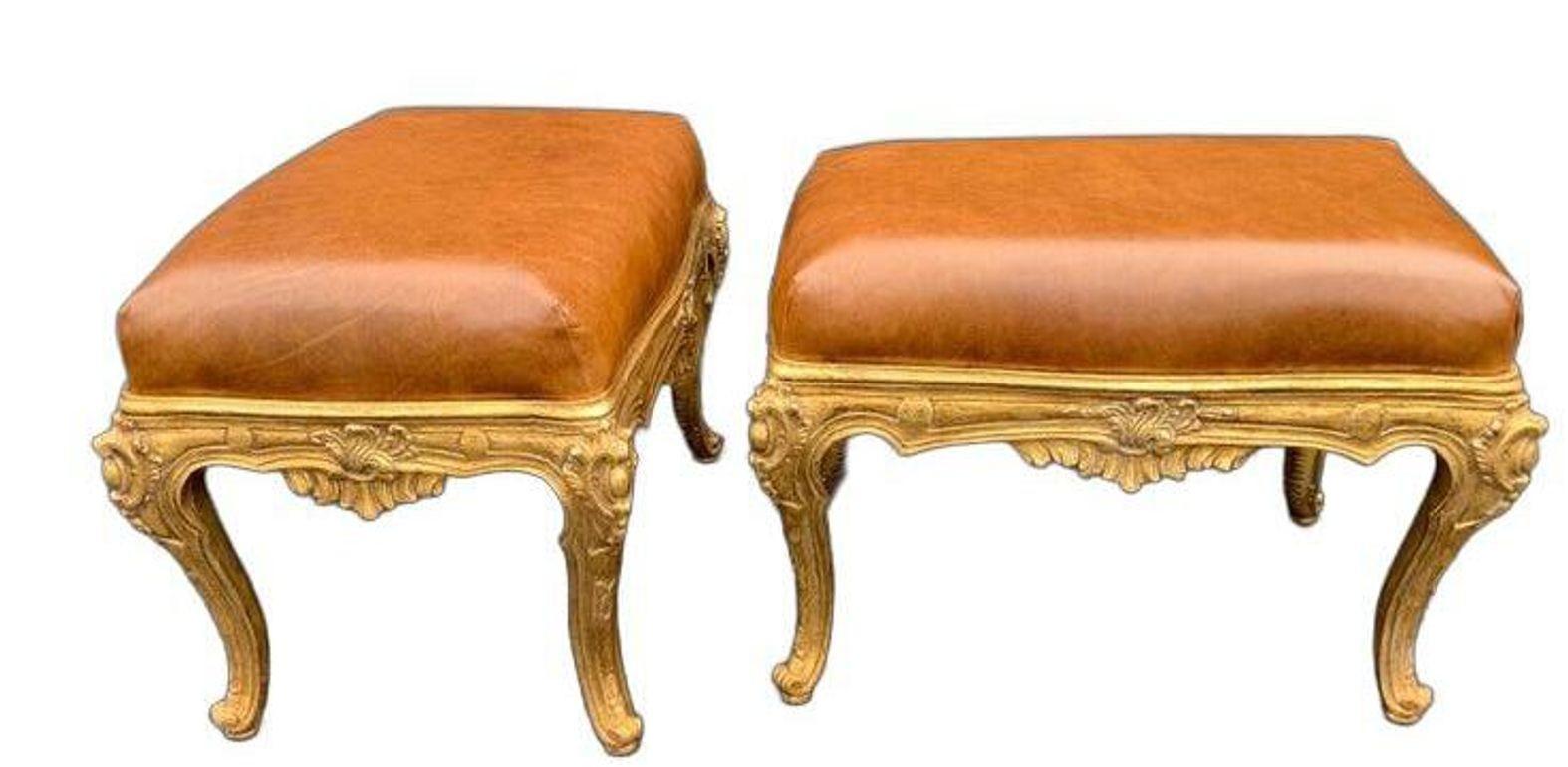 Elegante paire de bancs italiens sculptés à la main, richement dorés et garnis de cuir brun souple. Les montures présentent un travail détaillé et des motifs classiques, reflétant un savoir-faire traditionnel avec une finition luxueuse. La patine