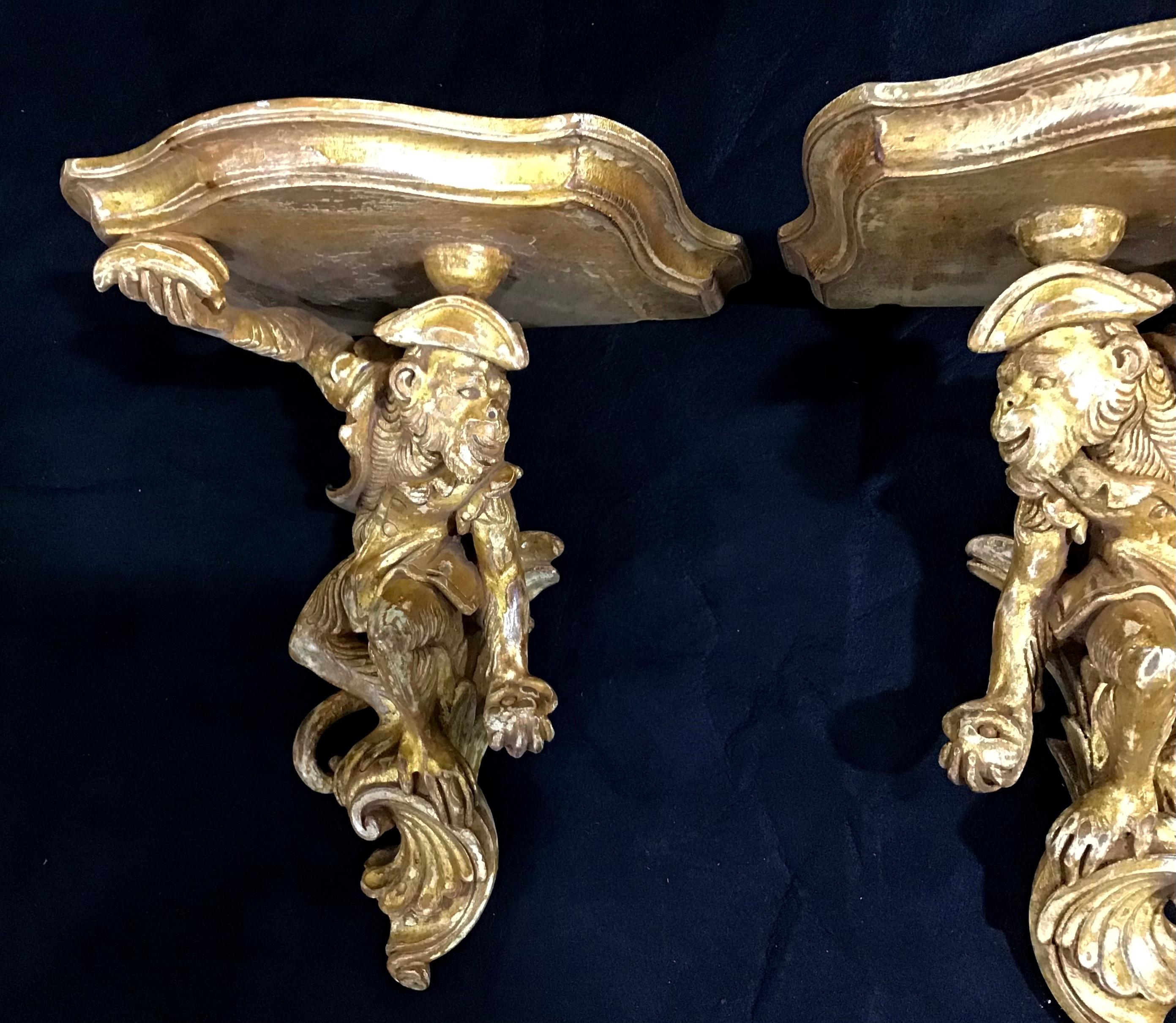Stunning pair of vintage Italian carved and giltwood opposing monkey wall consoles. These whimsical hand carved giltwood wall brackets have a wonderfully worn patina. Large top surface area.