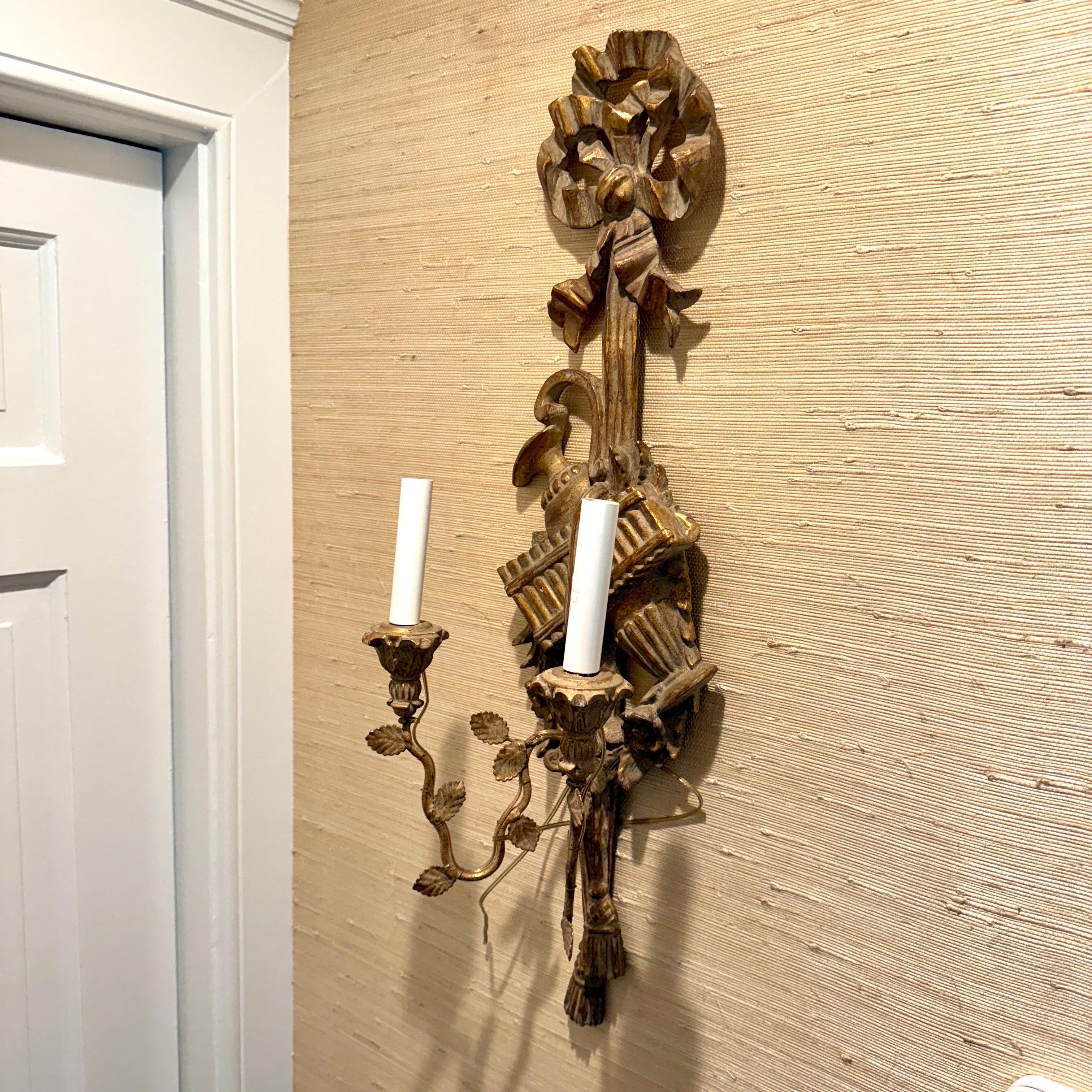 Set of Two Giltwood Wall Candle Sconces, 1960's Italy. Elegant wall sconces with beautiful detail throughout, including bows and ribbons as well as leaves and tassels. The hand-painted gold gilt finish on this pair has a very pleasing aged look.