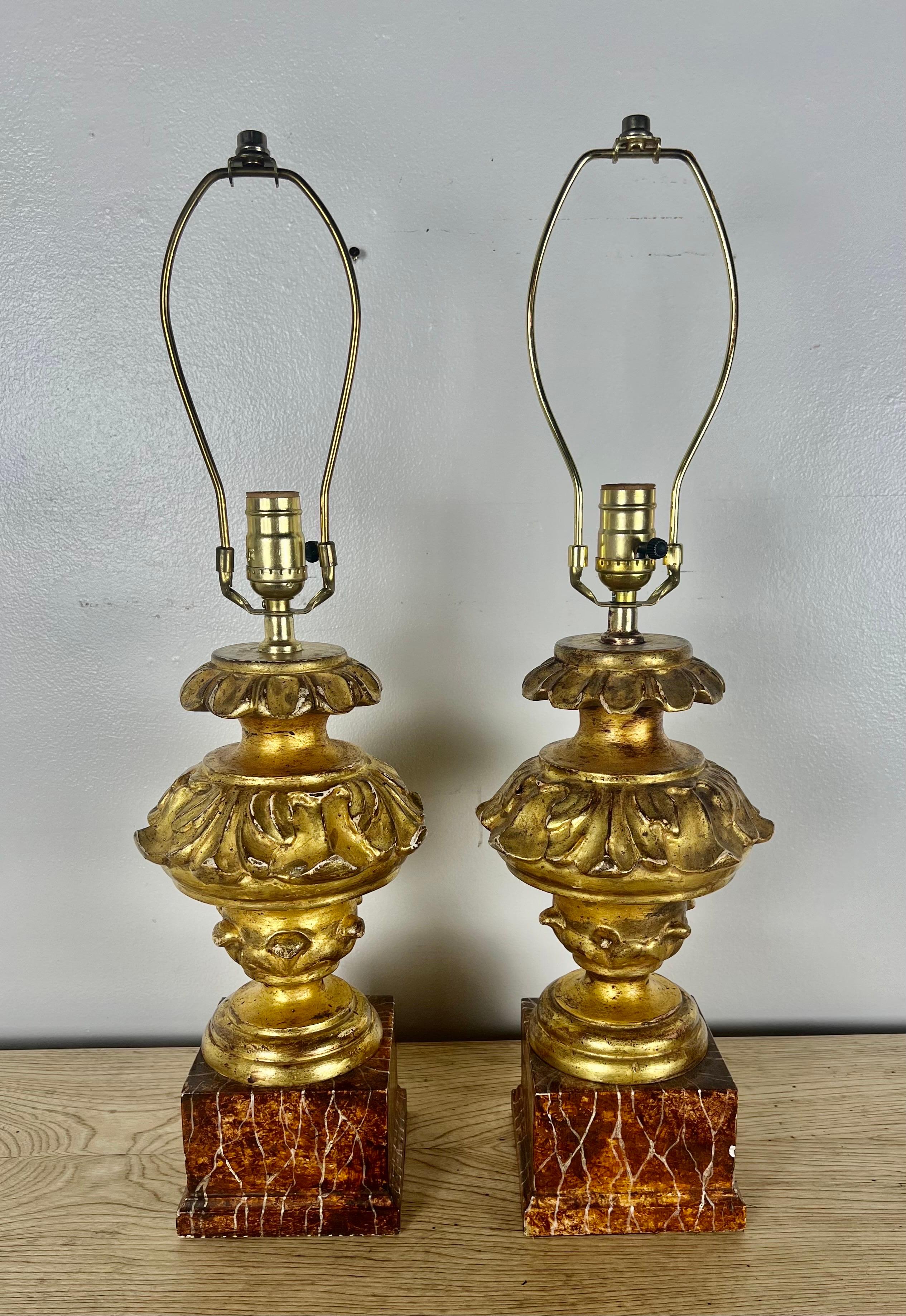 Pair of Carved Giltwood Italian Neoclassical style lamps on faux marble bases. The lamps are wired and in working condition.  No shades included.