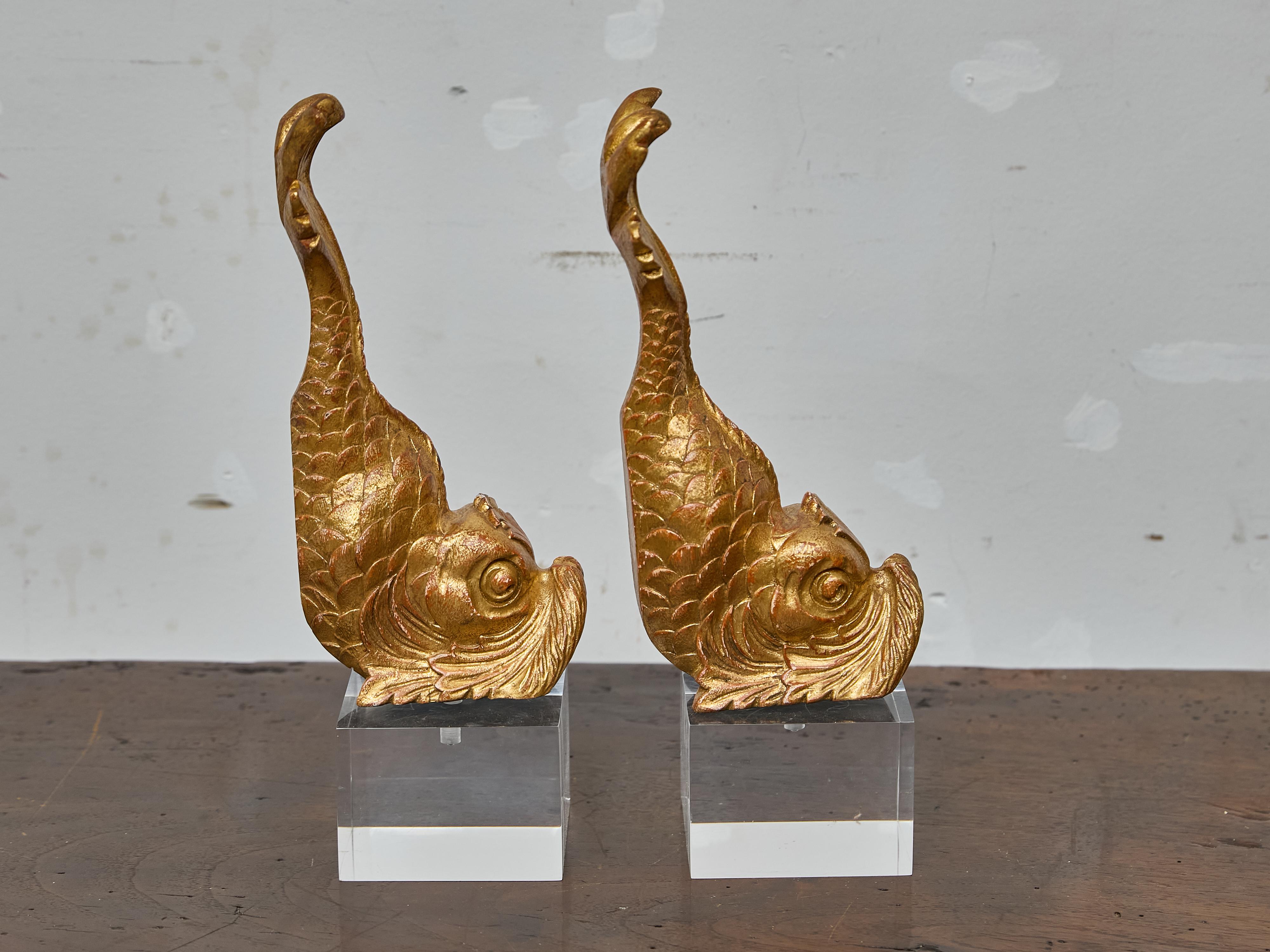 This striking pair of table lamps features 19th-century Italian carved wood fragments in the form of stylized dolphins, now mounted on custom Lucite bases and professionally rewired for use in the United States. Originally part of a larger