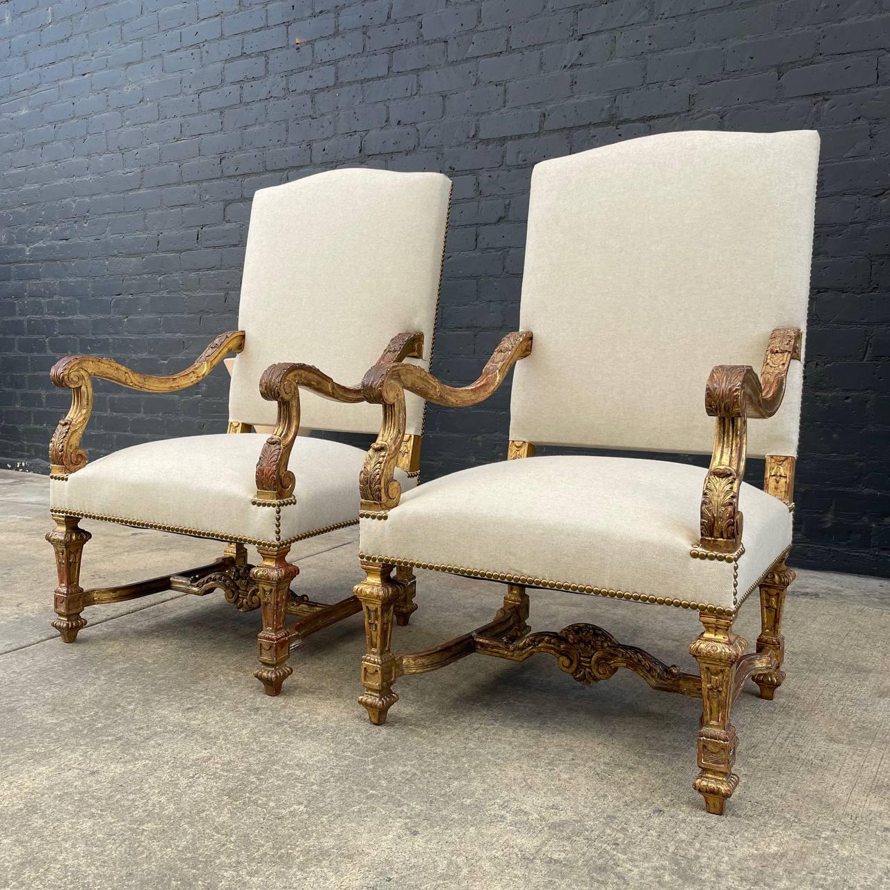 Luxurious, pair of early 20th century Italian carved giltwood armchairs in the Louis XIV style. These exquisitely carved chairs have been newly upholstered in a linen fabric which is soft to the touch and rich in texture. Antiqued brass nailhead