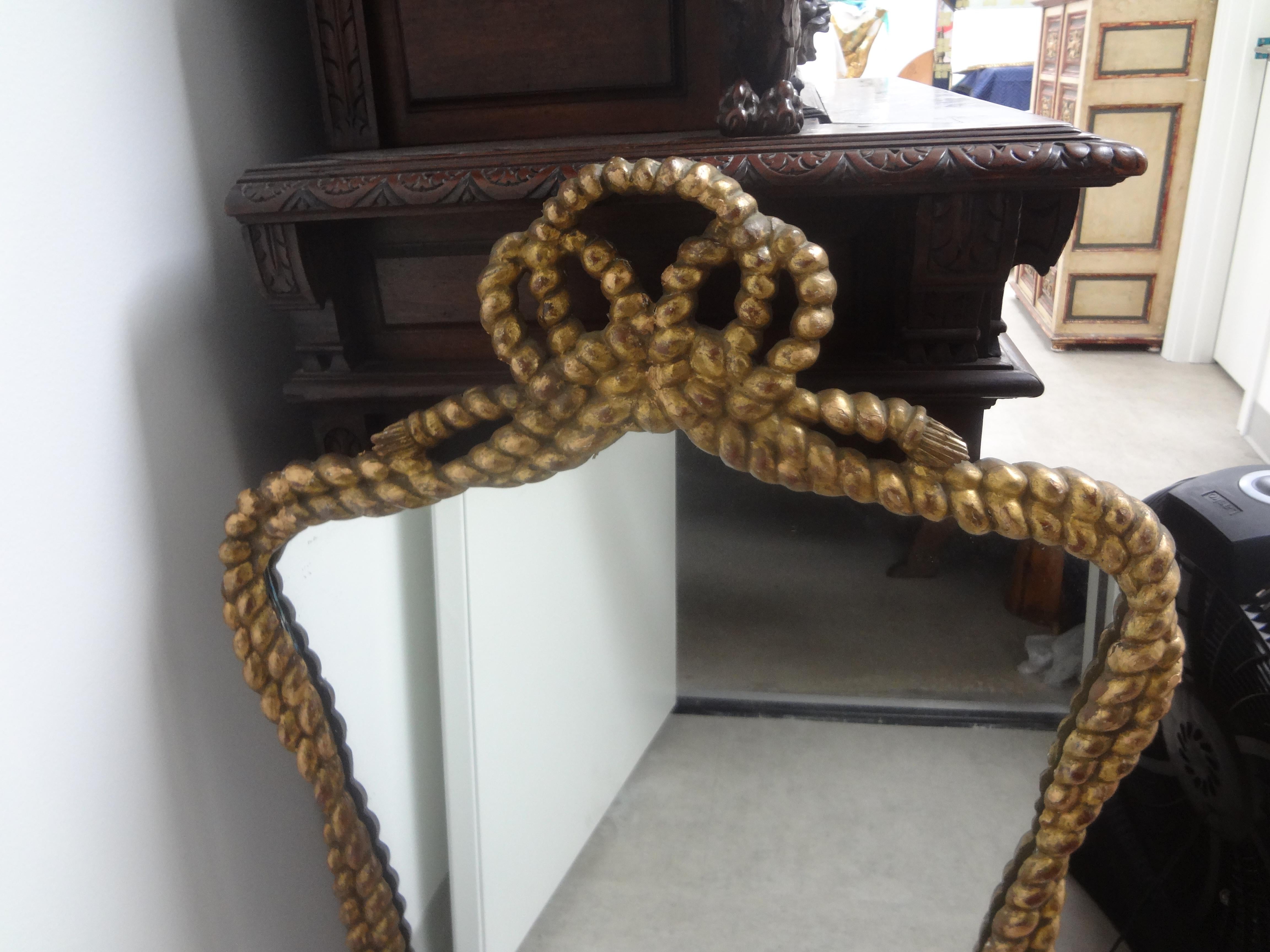 Pair of Italian giltwood rope and tassel mirrors. This stunning matching pair of Italian Hollywood regency carved gilt wood rope and tassel mirrors will work over consoles, commodes, buffets or credenzas in a variety of interiors.