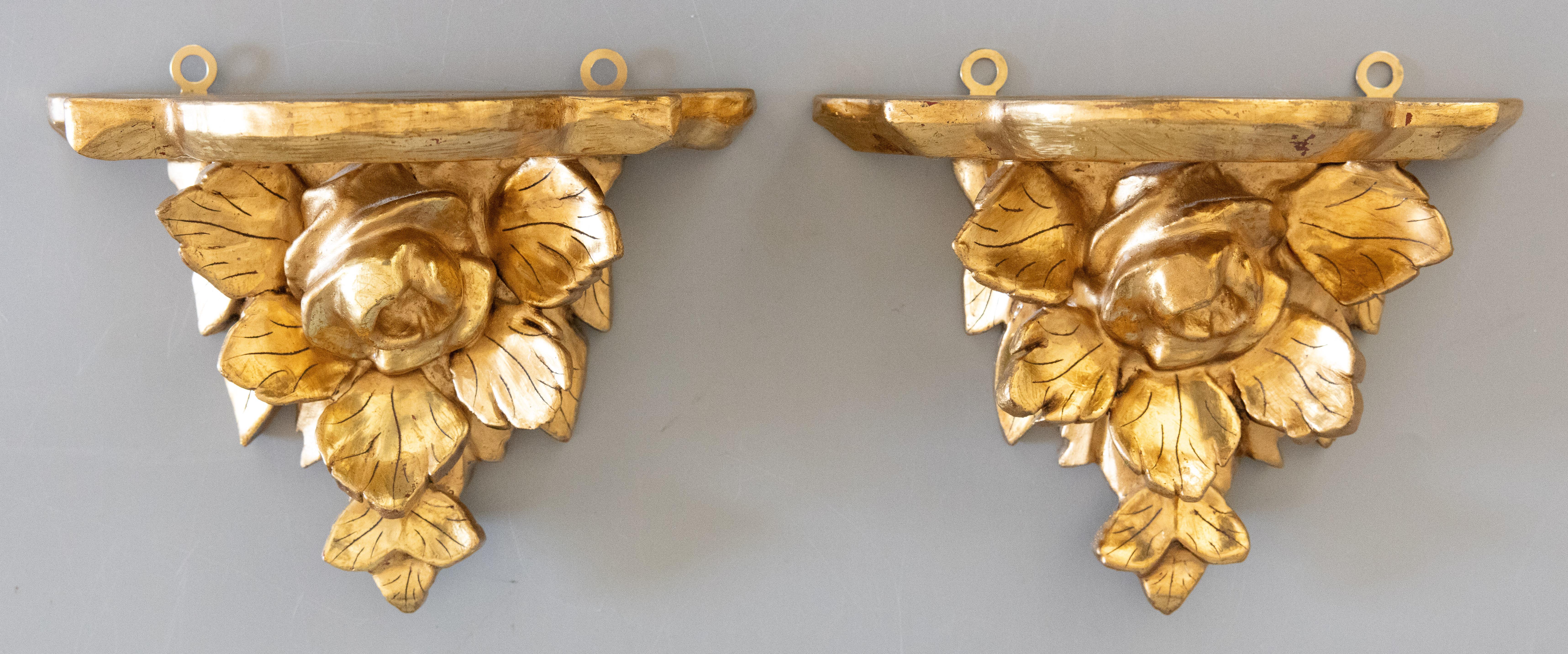 A lovely pair of vintage Italian gilded wood and gesso wall brackets shelves, circa 1940. They are decorated with lovely carved roses in a beautiful gilt patina, perfect for displaying decorative collectibles or fabulous on their