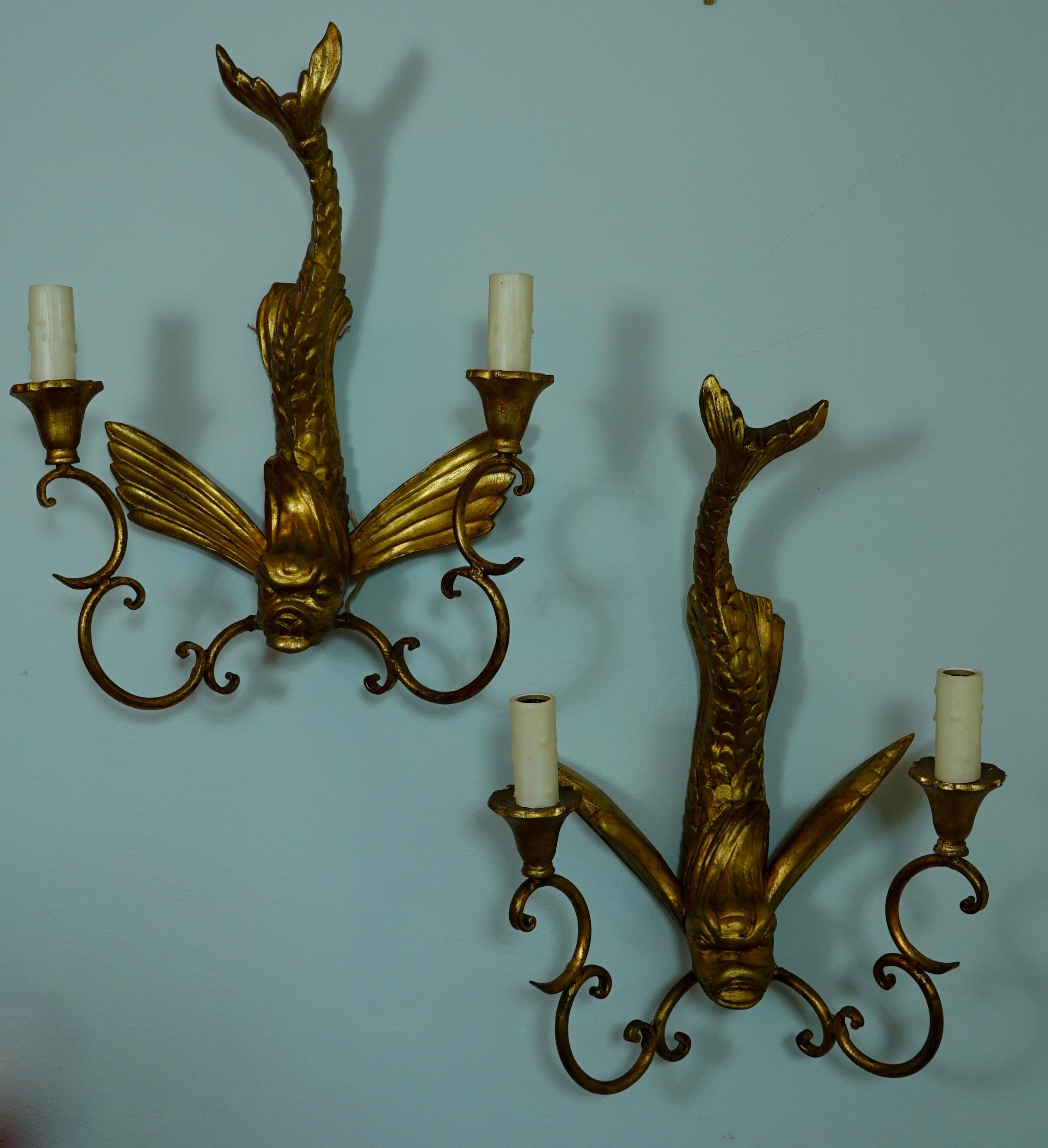 Pair of Italian carved giltwood sconces in the shape of mythical dolphins (midcentury). Each of the dolphins is unique, hand carved and slightly different (note the fins, forward and back). The sconces have two gilt metal arms comprising 
