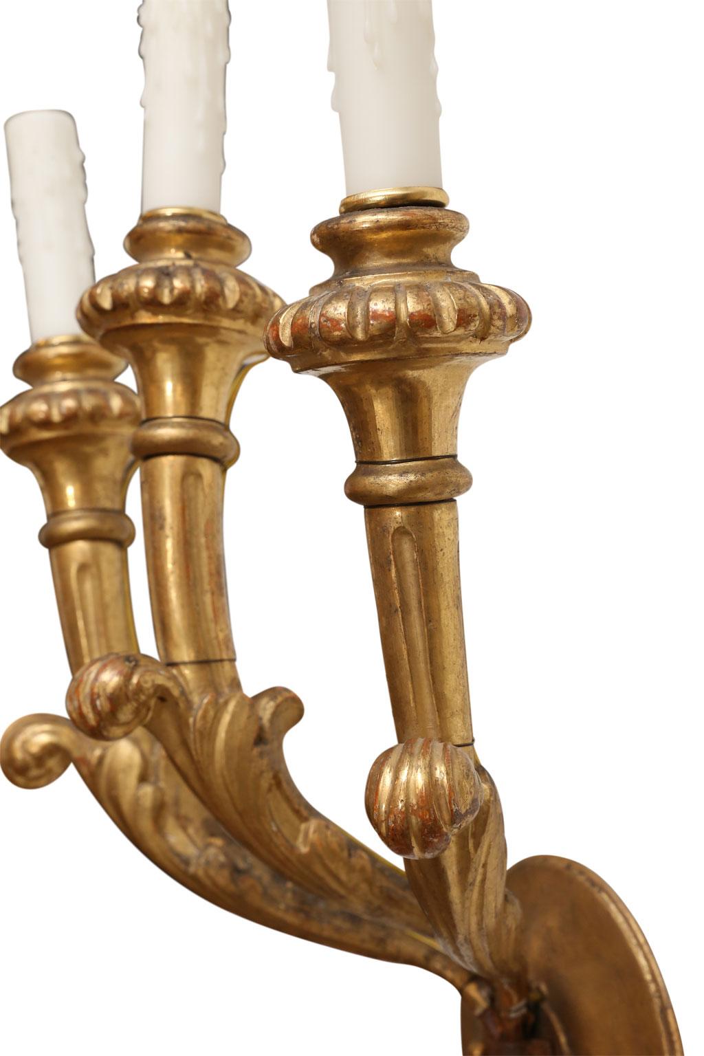 Pair of Italian giltwood sconces, hand-carved with three arms each and newly wired for use within the USA. Sconces include new back plates, finished to match sconces, to comply with UL Standard.