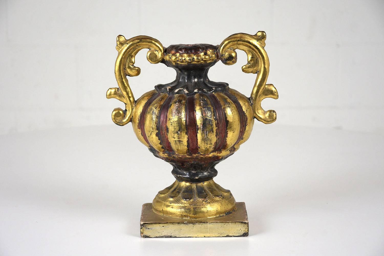 This pair of 1840s Italian Renaissance-style urns are carved from gilded wood with red and black accents. The urns feature classical motifs of acanthus leaves and scalloped edges. This pair of urns is sturdy, stunning, and ready to decorate any home
