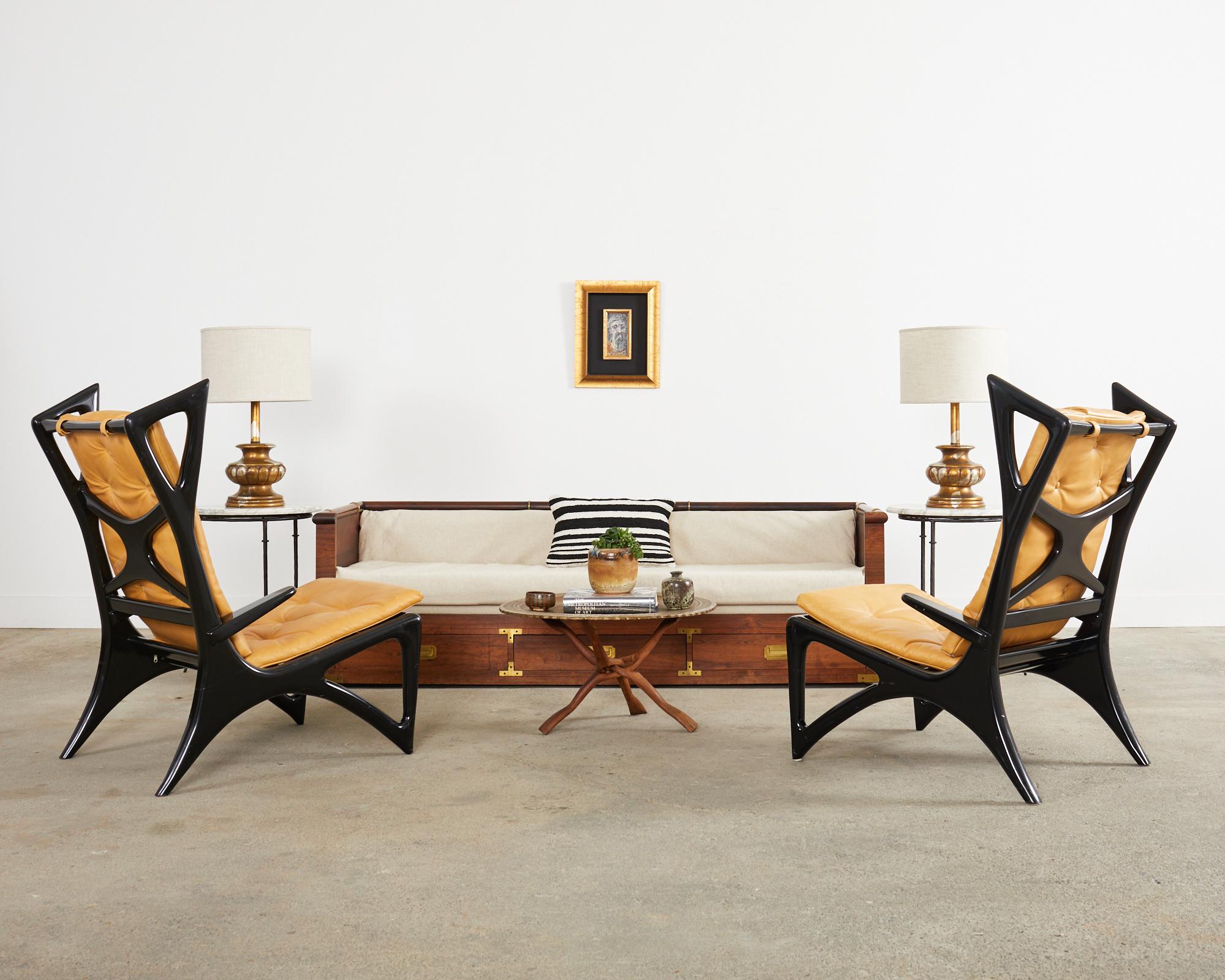 Dramatic pair of Italian Mid-Century Modern sculptural lounge chairs or wing chairs featuring a black lacquer ebonized finish. These radically redesigned wing chairs have gracefully curved frames with triangular wings and legs. The slanted ergonomic