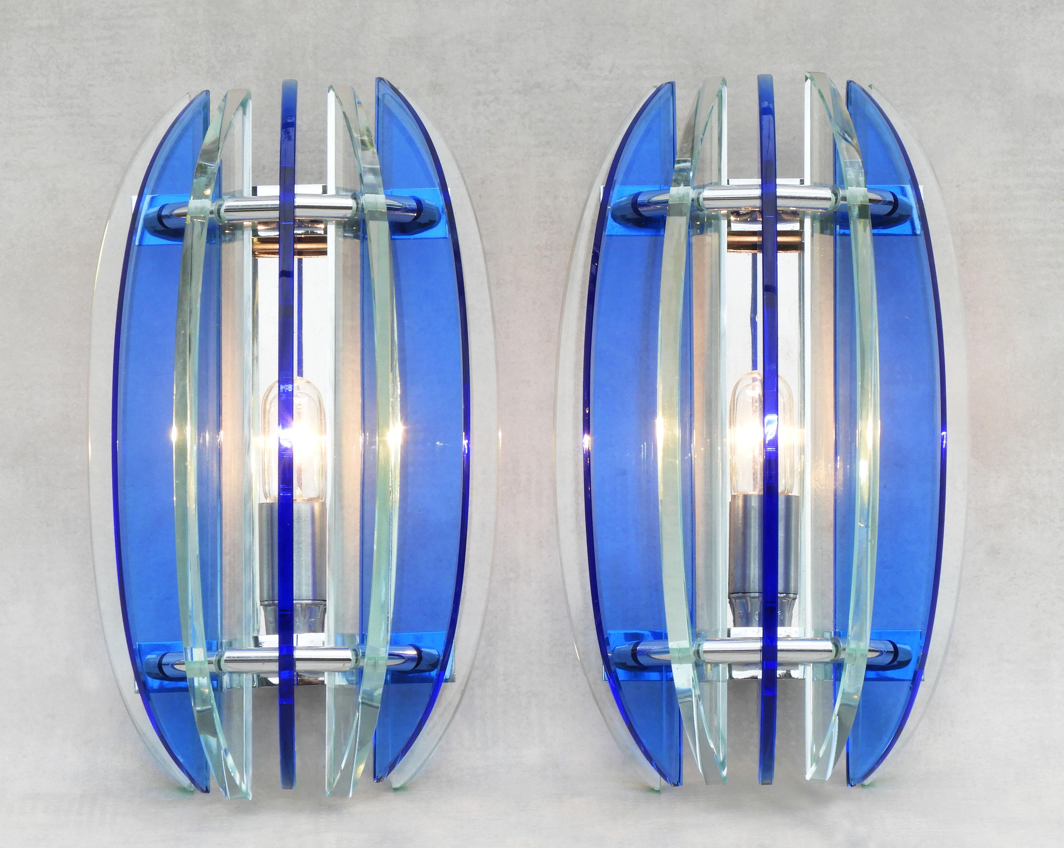 Pair of Veca glass wall lights mid century Italy, circa 1970

Two mid-century wall light sconces from Italian lighting company Veca.
Seven alternating blue and clear/pale green glass crescents in a semicircular form on a chromed frame structure.  In