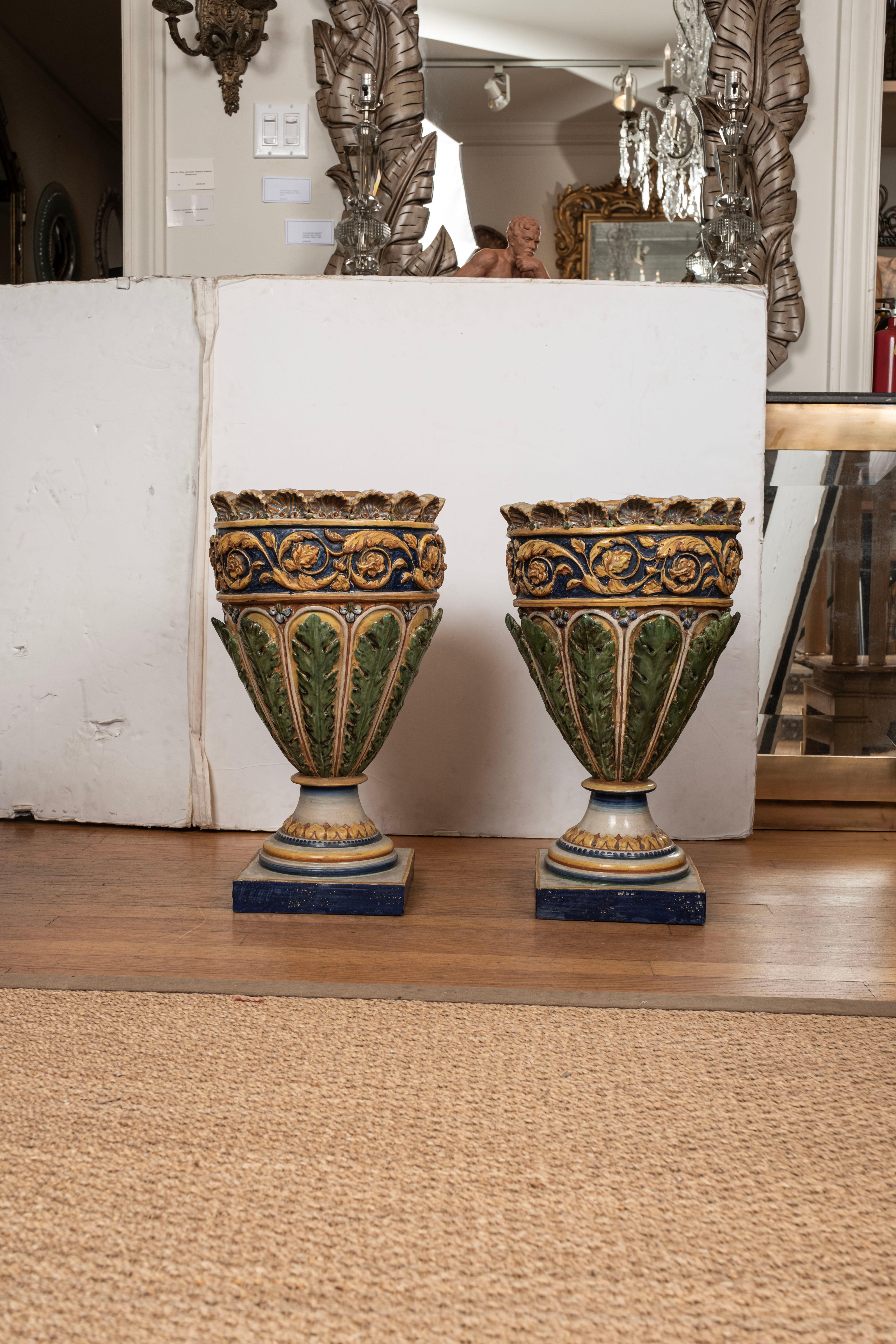 Pair of Italian glazed terracotta urns or planters.
This stunning pair of Italian glazed terracotta urns, planters or jardinieres are from the Amalfi coast and feature beautiful blues, golds, green and cream colors with a shell motif. Lovely as