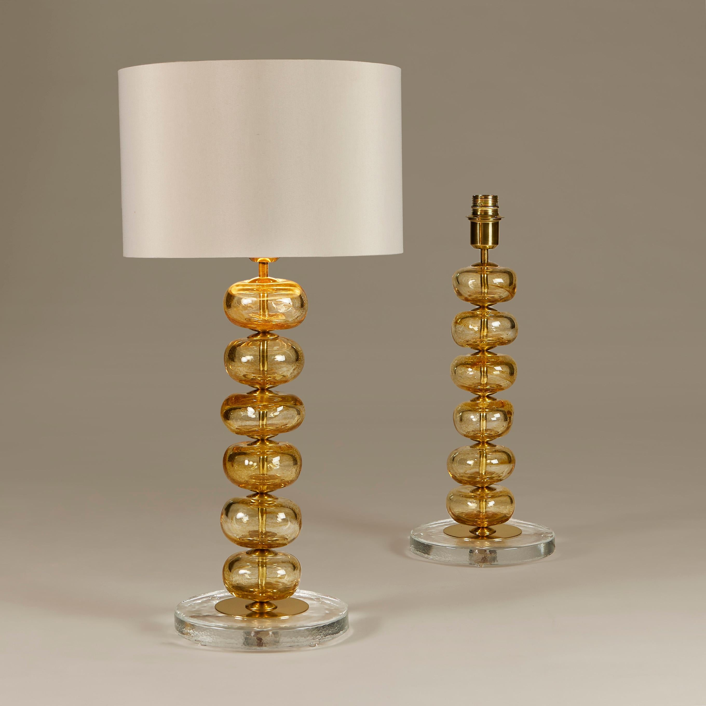 Elegantes Paar Tischlampen, bestehend aus sechs mundgeblasenen Murano-Glasscheiben in zartem Gold mit Messingdetails dazwischen. Steht auf einem runden Sockel aus Klarglas und Messing.

Aufgrund der handgefertigten Natur des Glases sind keine zwei