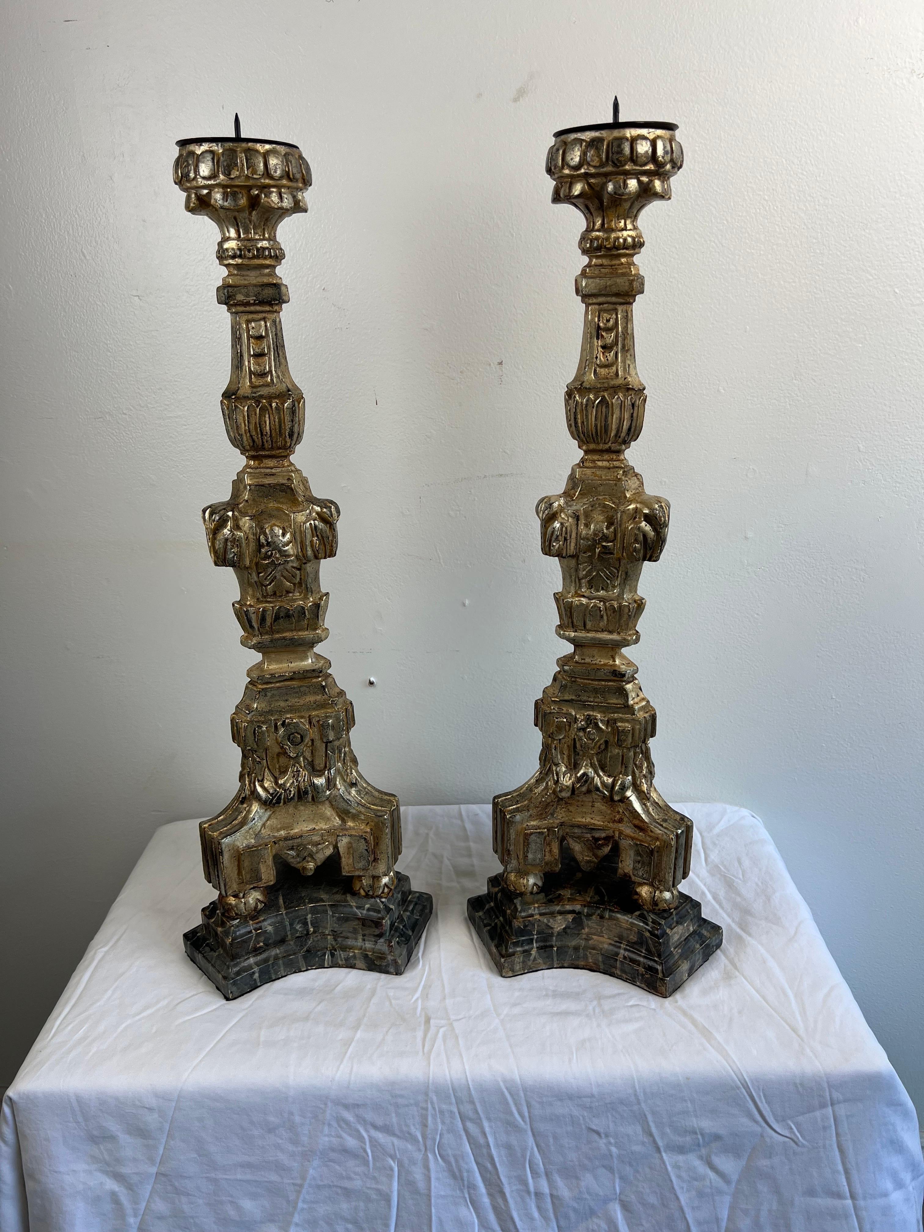Early 20th Century pair of Italian silver & gold gilt candlesticks.  There is some wear to the gilt finish but overall they beautiful.  The carving depicts flowers, swags, and so much more. Metal bobeches with tiny prickets.The candlesticks stand on