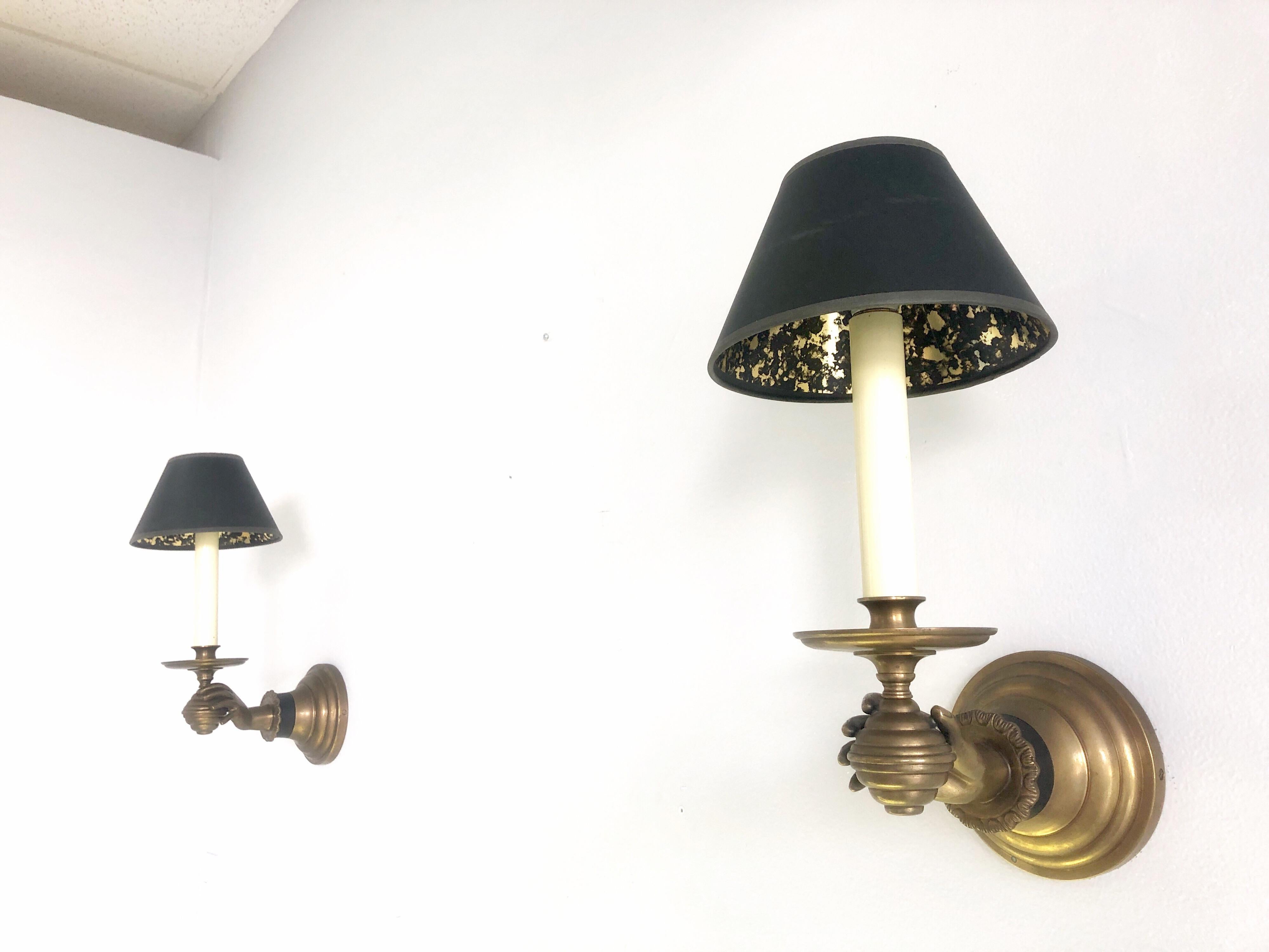 A true pair of brass sconces, a graceful hand holding the light source. Retain vintage black shades. In working order.