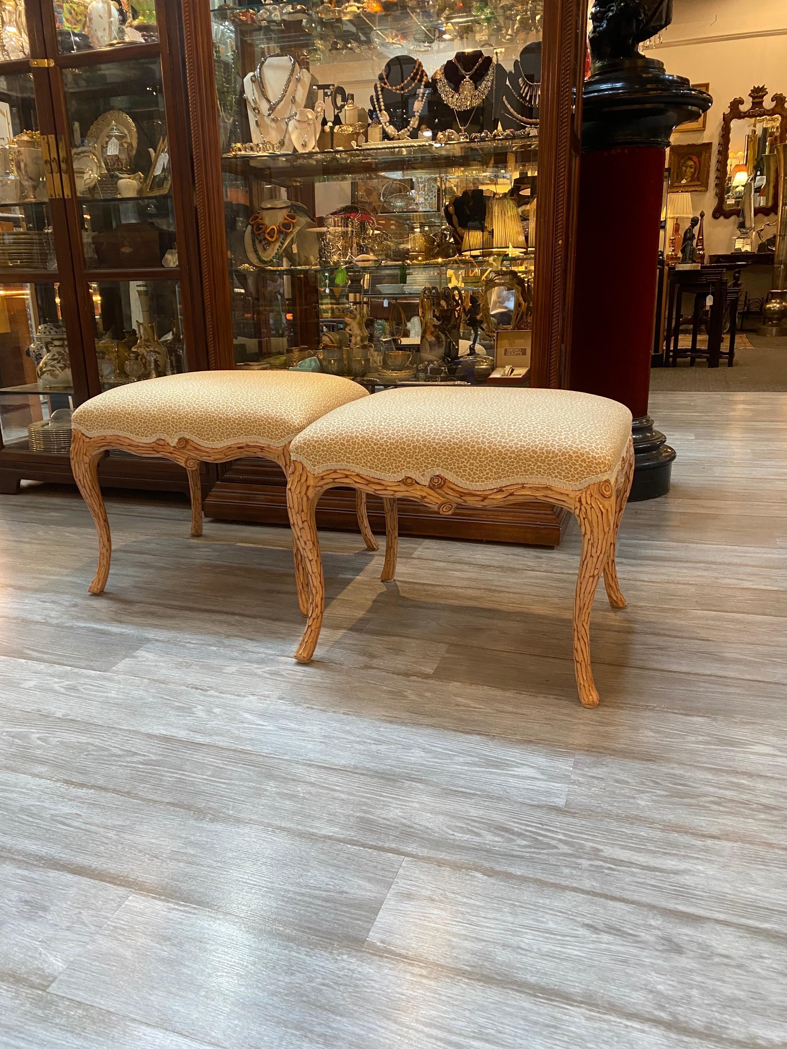 A pair of faux bois hand carved Italian ottomans. The frames with carved branch motive apron and curved legs in a natural color with a white washed finish. The new animal print fabric seats. Measures: 22 wide, 19.5 deep, 19 high.