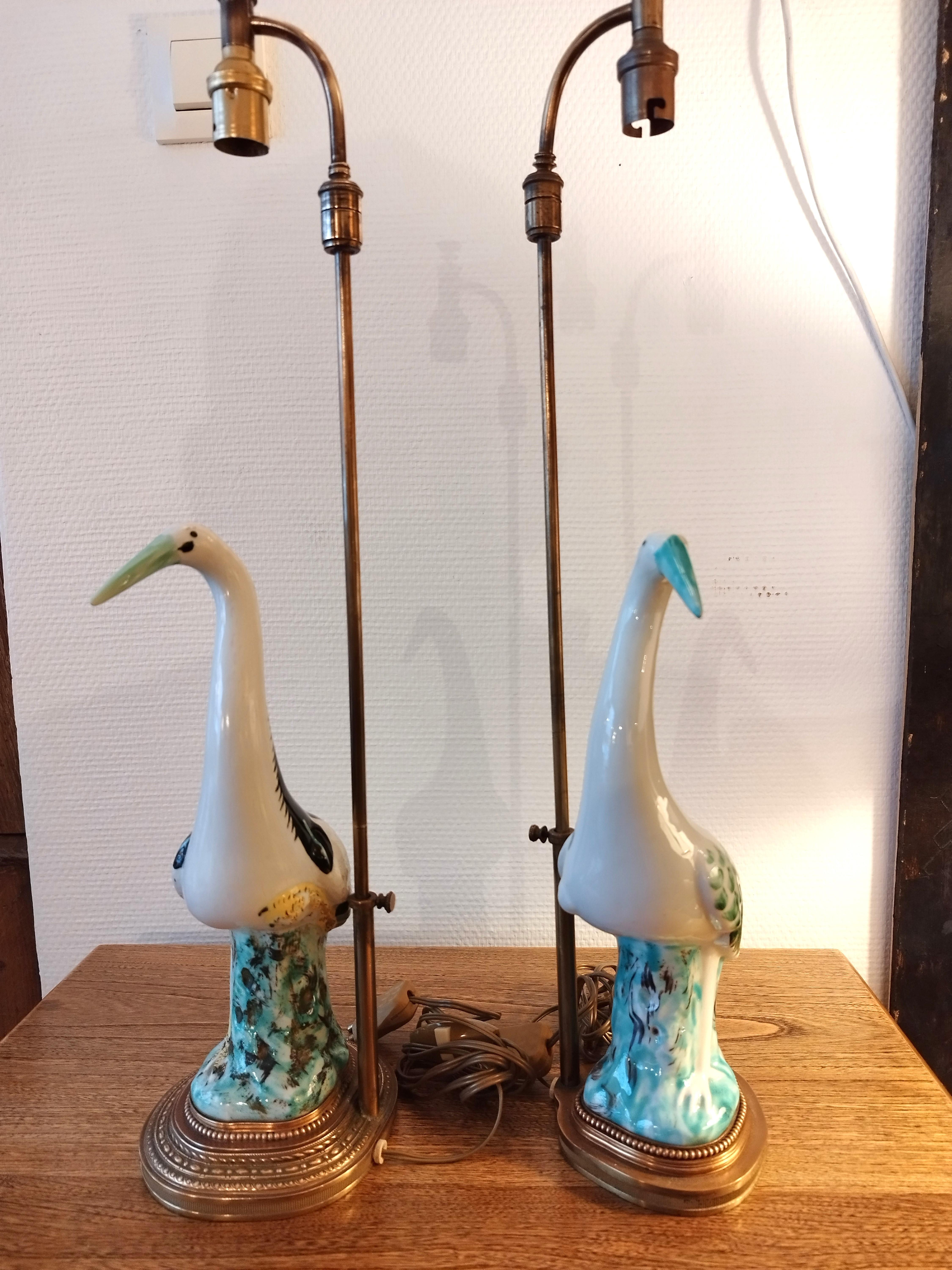 Faux pair of lovely lamps in ceramic (or porcelain ?) mounted on a gilt brass base, depicting 2 herons or storks. They are not matching, but of identical style and quality. The lamp shades have just been custom made to give the lamps a more modern