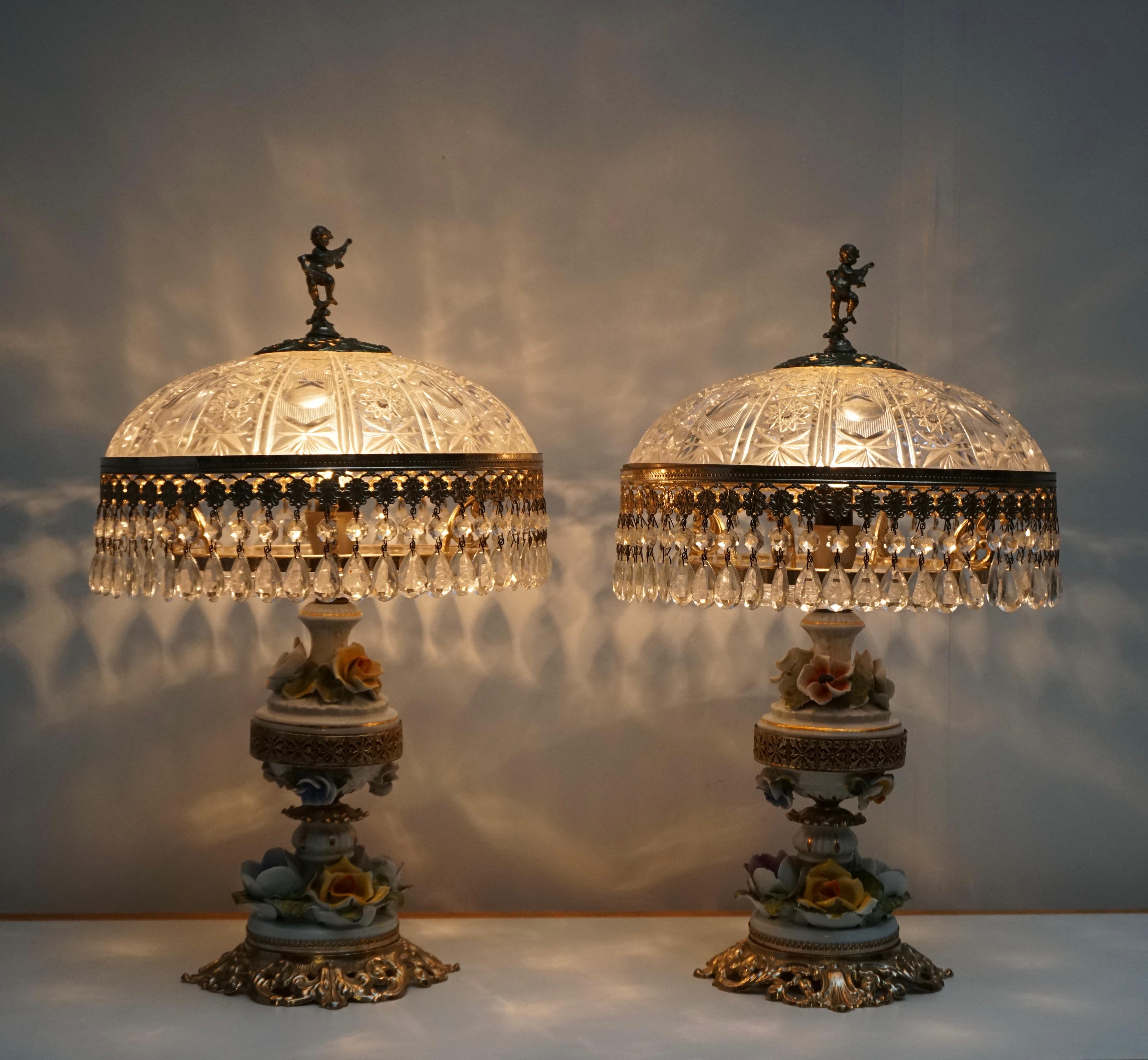 Two table lamps with a crystal shade and brass base decorated with porcelain flowers.
Measures: Diameter 32 cm.
Height 52 cm.