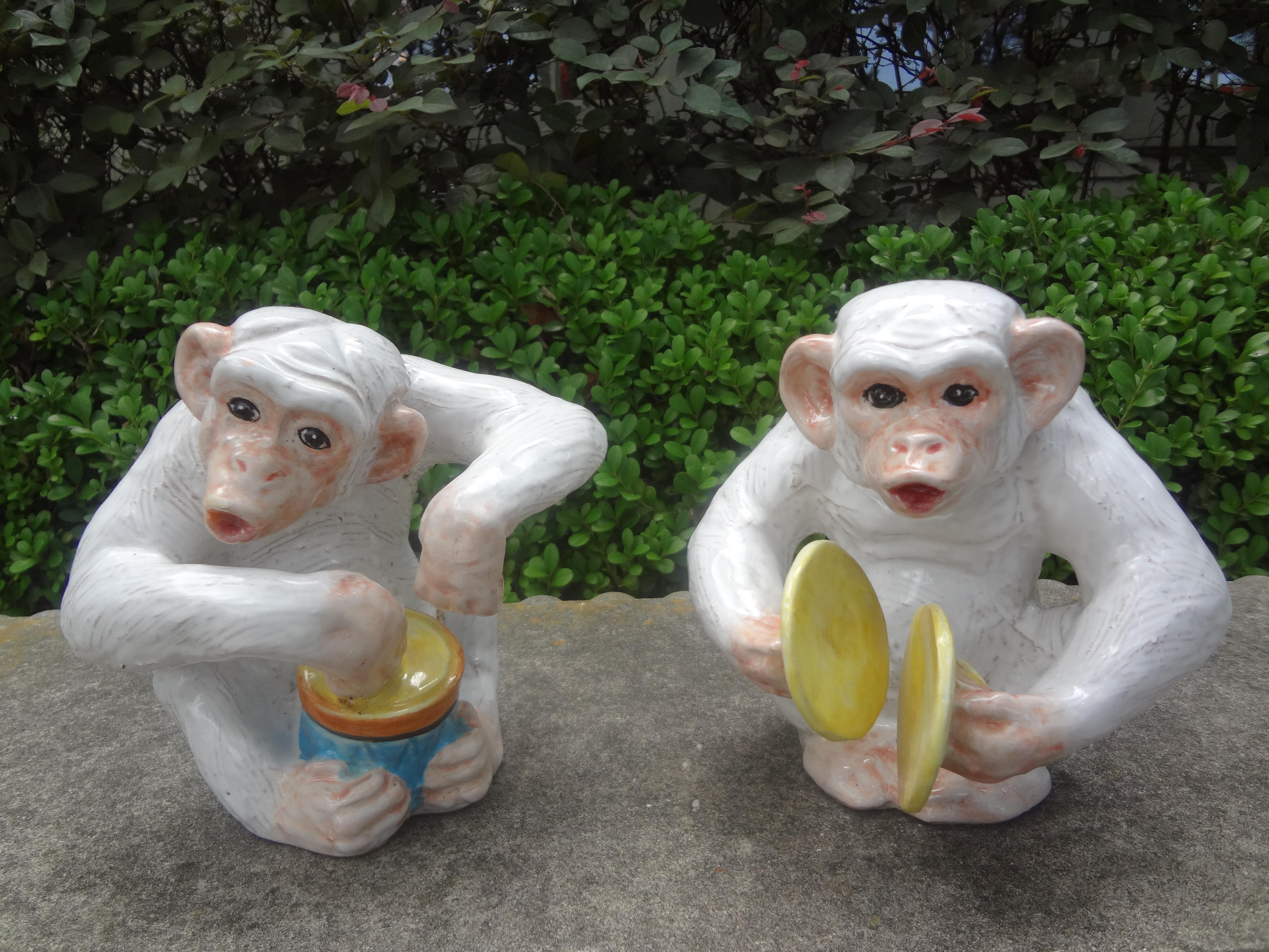 Whimsical pair of mid-century Italian glazed terra-cotta monkey figures or statues. These Hollywood Regency vintage monkey sculptures are playing musical instruments. One monkey is playing a drum, the other monkey cymbals.