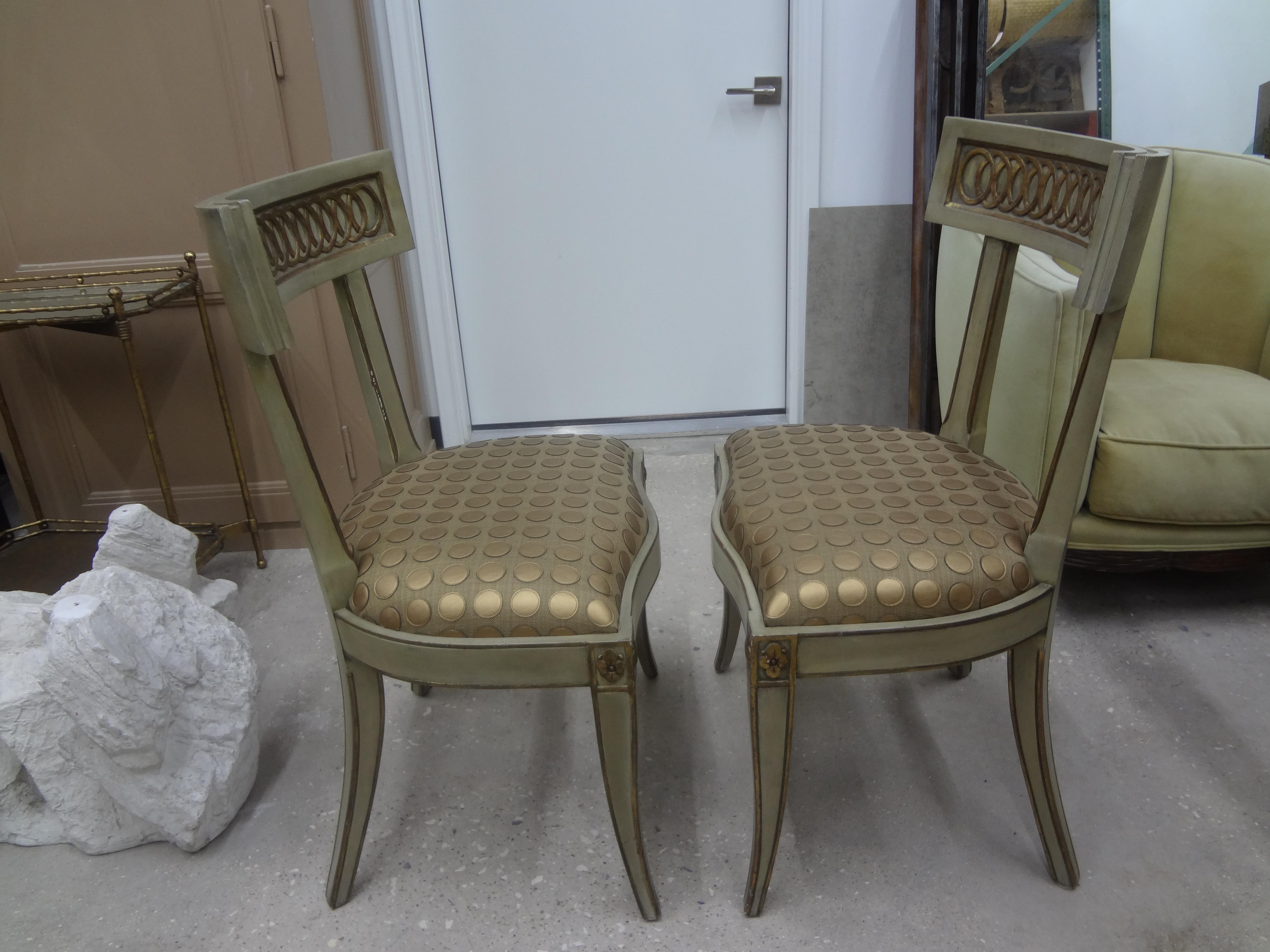 Stunning pair of Italian Hollywood Regency klismos style chairs. These chic high style Italian side chairs are painted a soft gray/green with gilt accents and have great splayed legs or saber legs. Our vintage Klismos chairs make great entrance