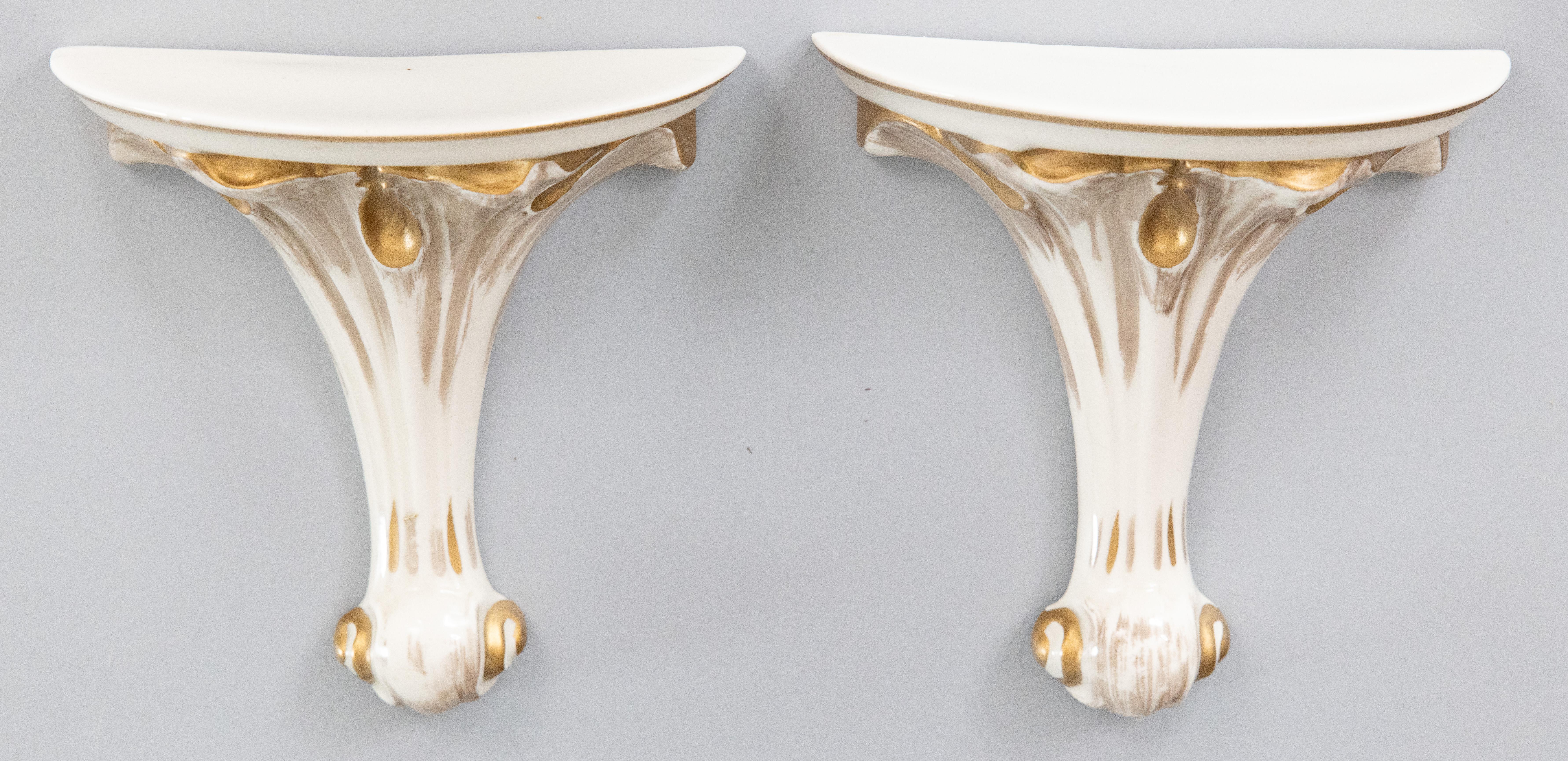 Una splendida coppia di mensole da parete in porcellana dorata e crema, circa 1950. Nello stile di Serge Roche e Dorothy Draper. Queste eleganti staffe hanno pennacchi svasati con accenti dorati e sono perfette per esporre oggetti decorativi da