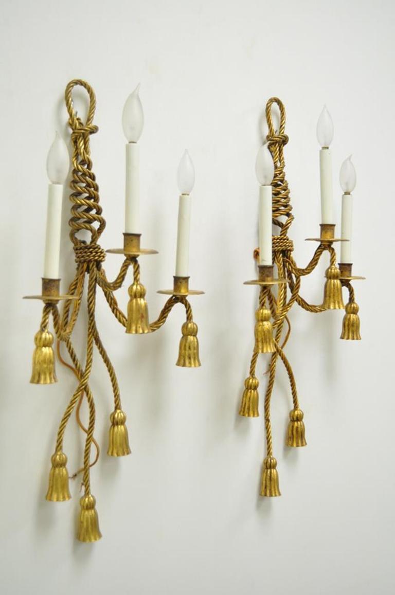 Pair of stunning Italian Hollywood Regency rope and tassel form lighted wall sconces. Item features beautiful gold gilt metal frames, three lights each, and elegant rope and tassel form, circa mid-20th century, Italy. Measurements: 28.5