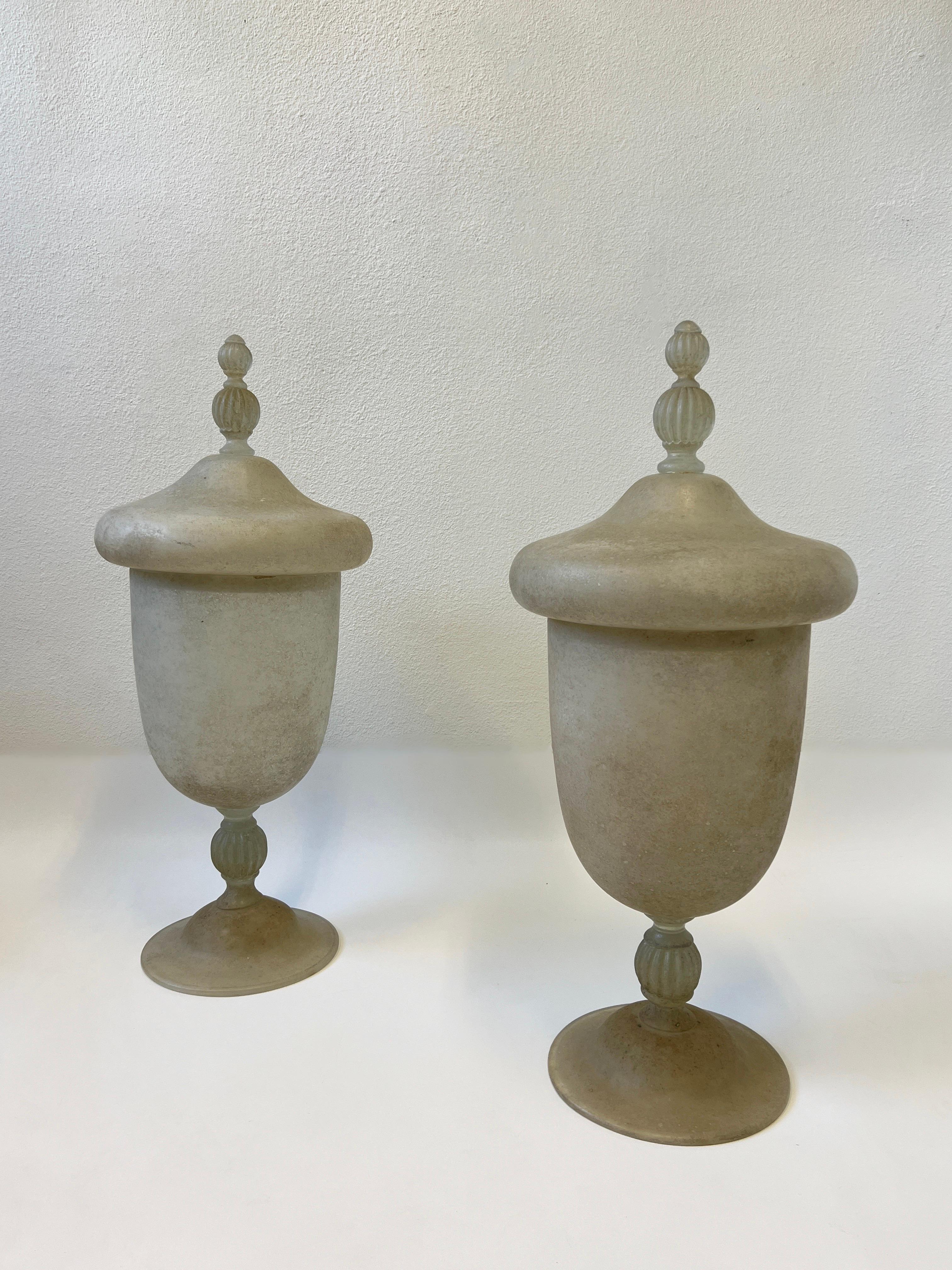 Pair of 1980’s Italian scavo Murano glass large vases or urns. 
They are in the style of Karl Springer. 
This are in beautiful condition no chips. They have a rough texture finish.
Measurements 34.5” High, 15” Diameter, 11.5” Diameter at bottom